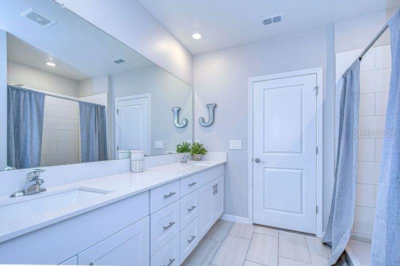 Double sink vanity with a walk in shower.