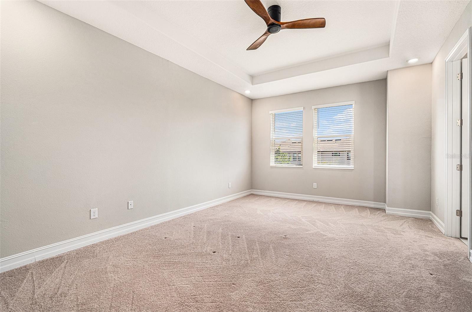 Spacious primary bedroom with tray ceiling