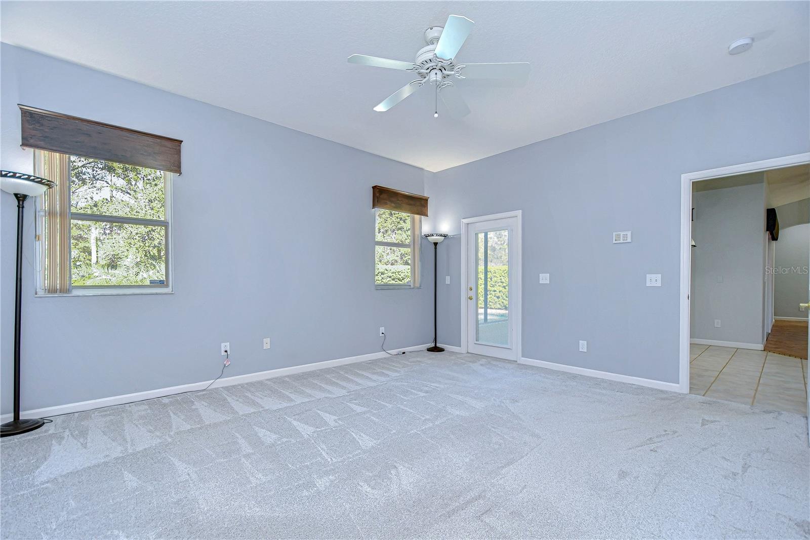 Serene and spacious, this light-filled primary bedroom boasts fresh carpet and a calming palette.