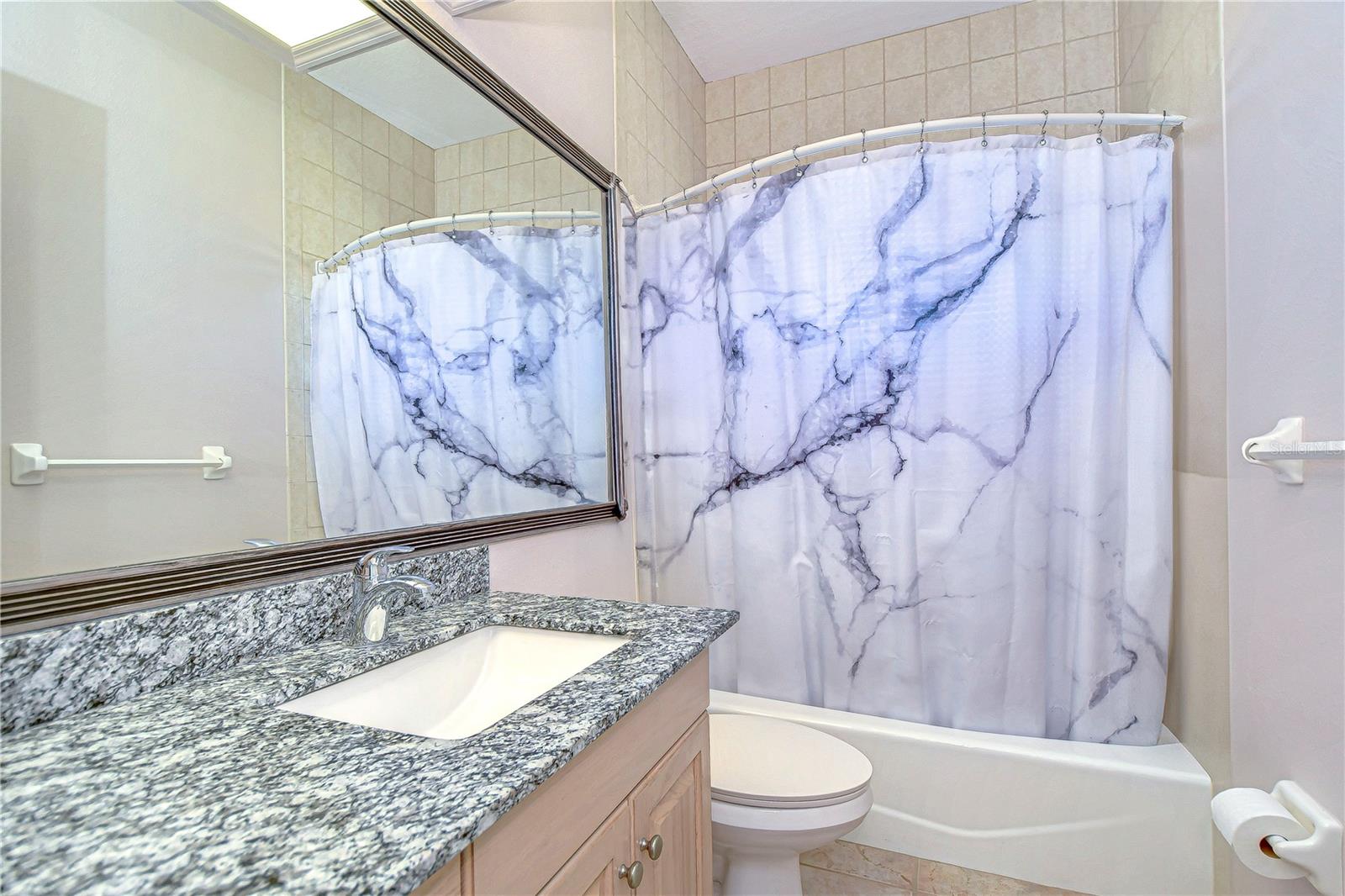 Step into elegance with this bathroom's stunning granite countertop