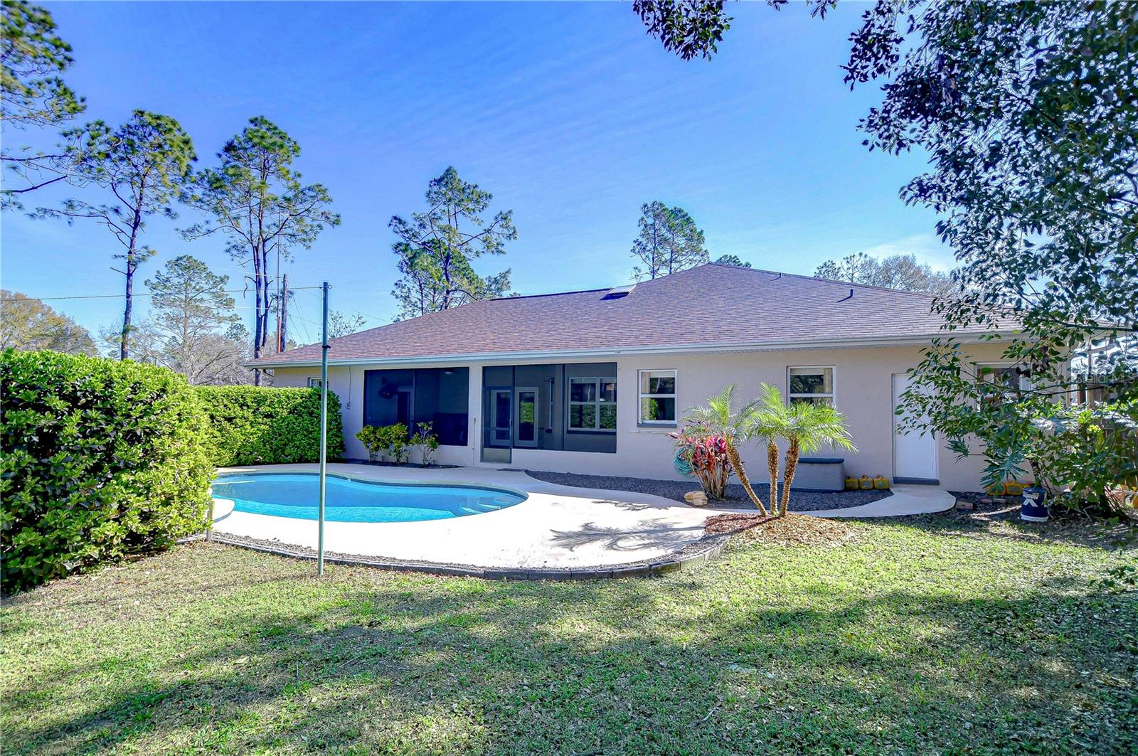 Dive into serene living with this charming backyard oasis, featuring a sparkling pool and lush greenery.