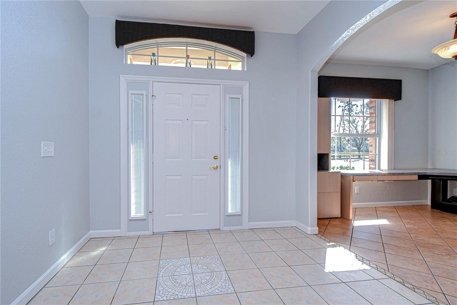 Step into this luminous entryway, where tile flooring and an arched window set a welcoming tone.