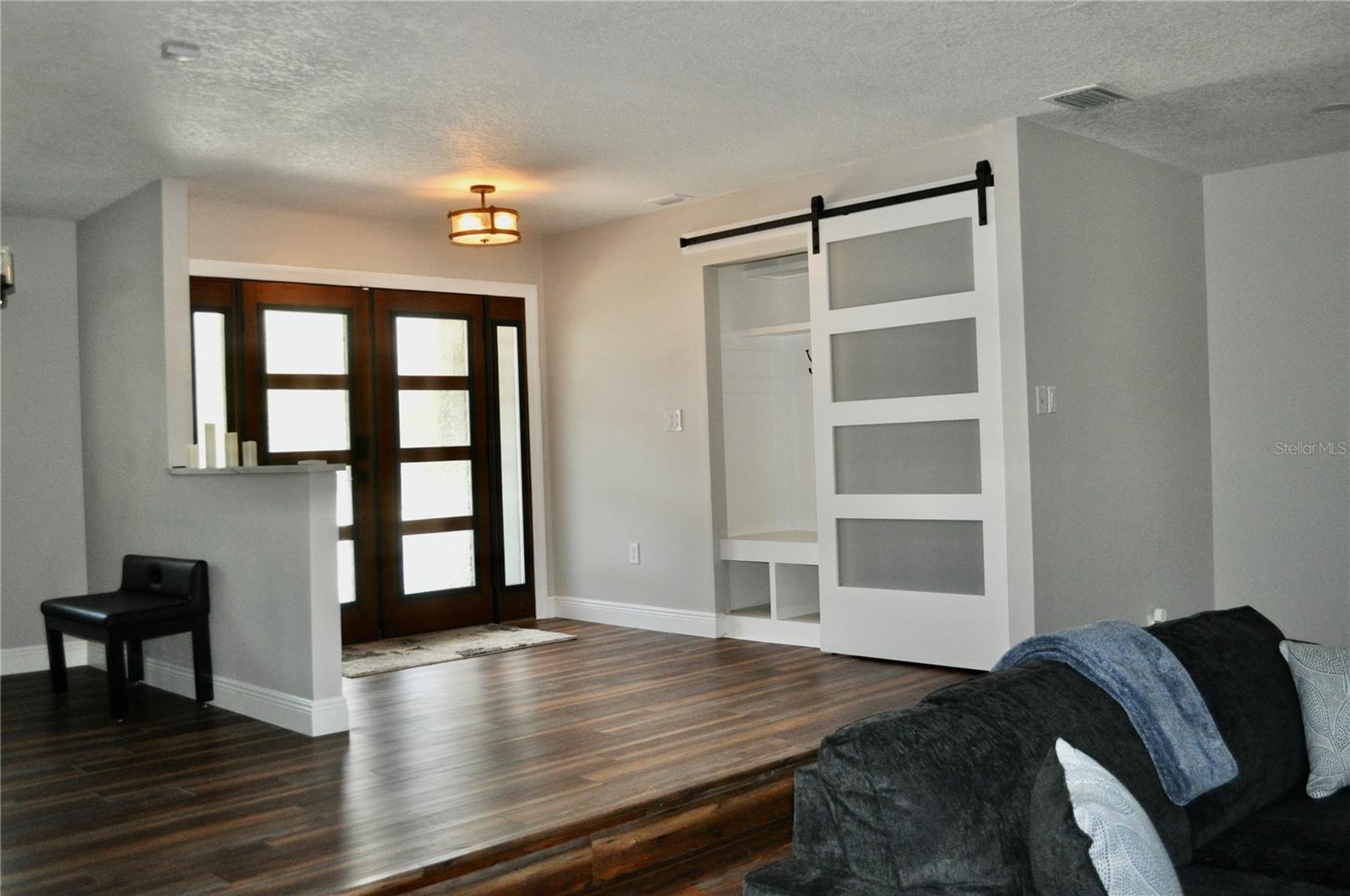 Entry way foyer / stylish built-in mudroom cabinet cleverly tucked behind sliding barn door offering storage and providing seclusion and privacy for back bedrooms.