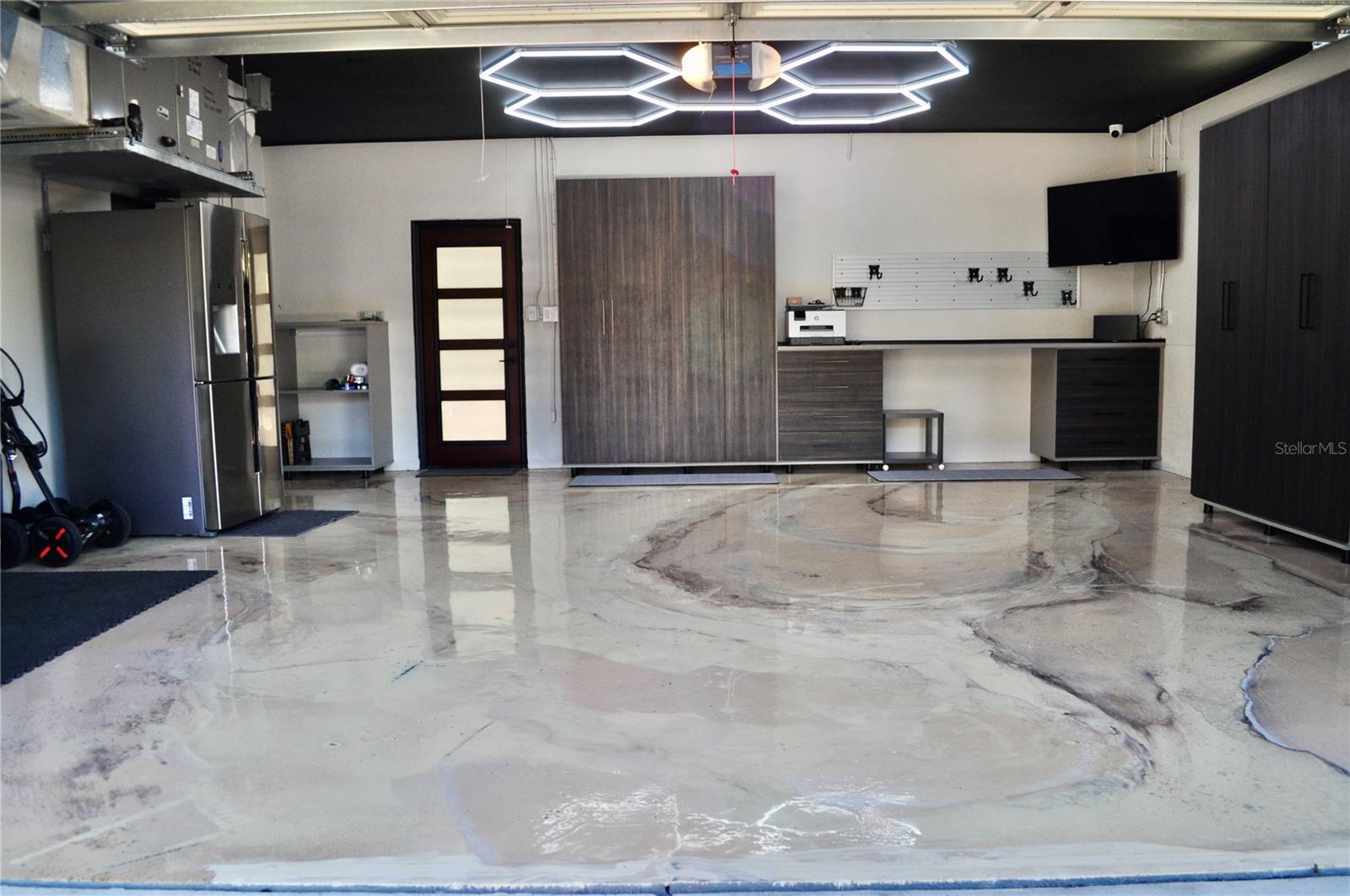 2 car attached house garage w/ EV charging station. Visually striking marble-designed epoxy flooring with workstation and cabinetry offering ample space for projects, organization, hobbies or recreational game of ping-pong!