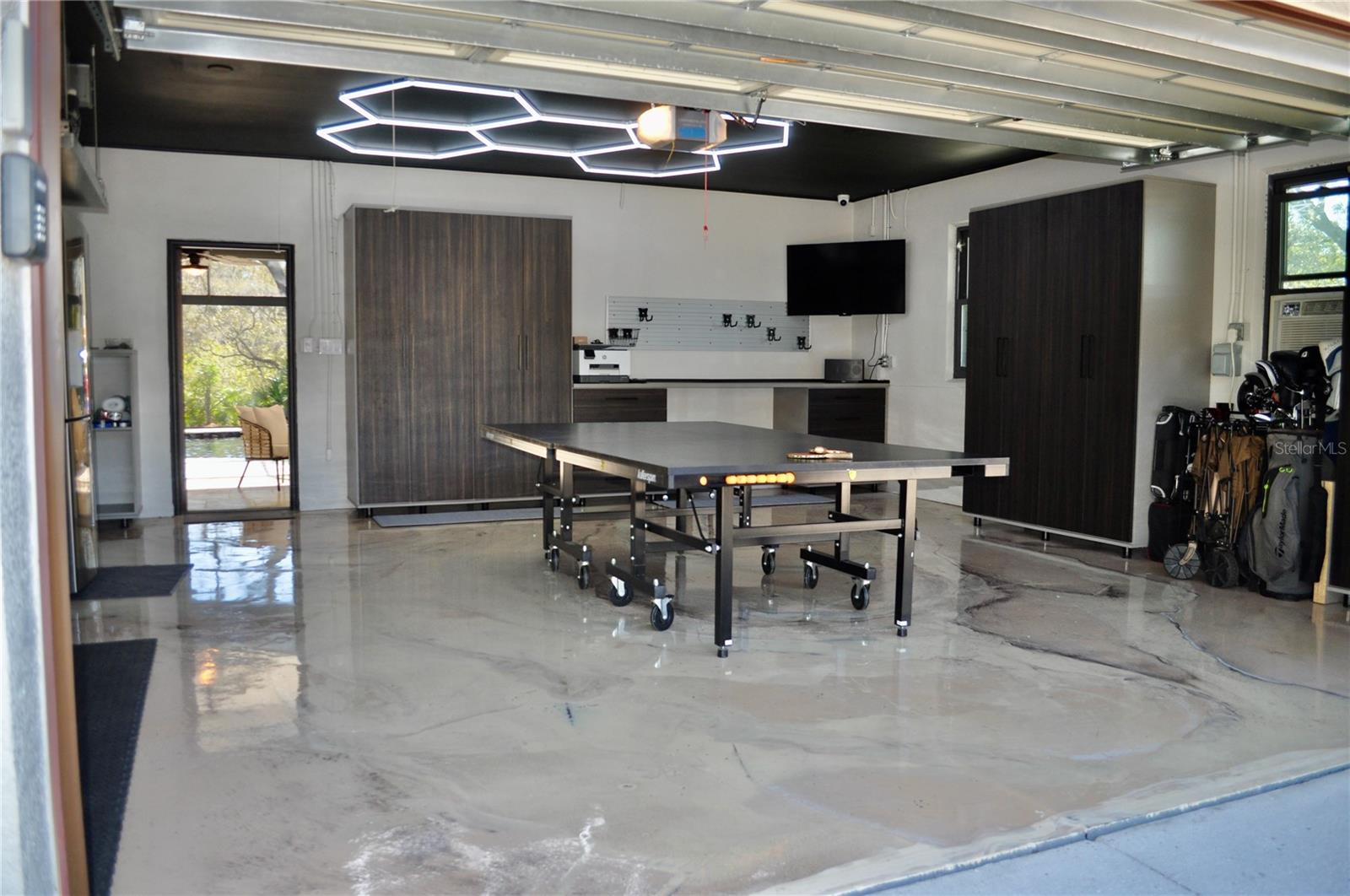 2 car attached house garage w/ EV charging station. Visually striking marble-designed epoxy flooring with workstation and cabinetry offering ample space for projects, organization, hobbies or recreational game of ping-pong!