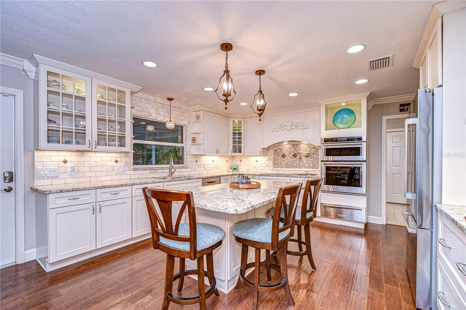 Step into culinary bliss with this elegant kitchen featuring granite countertops, chic pendant lighting, and double ovens.