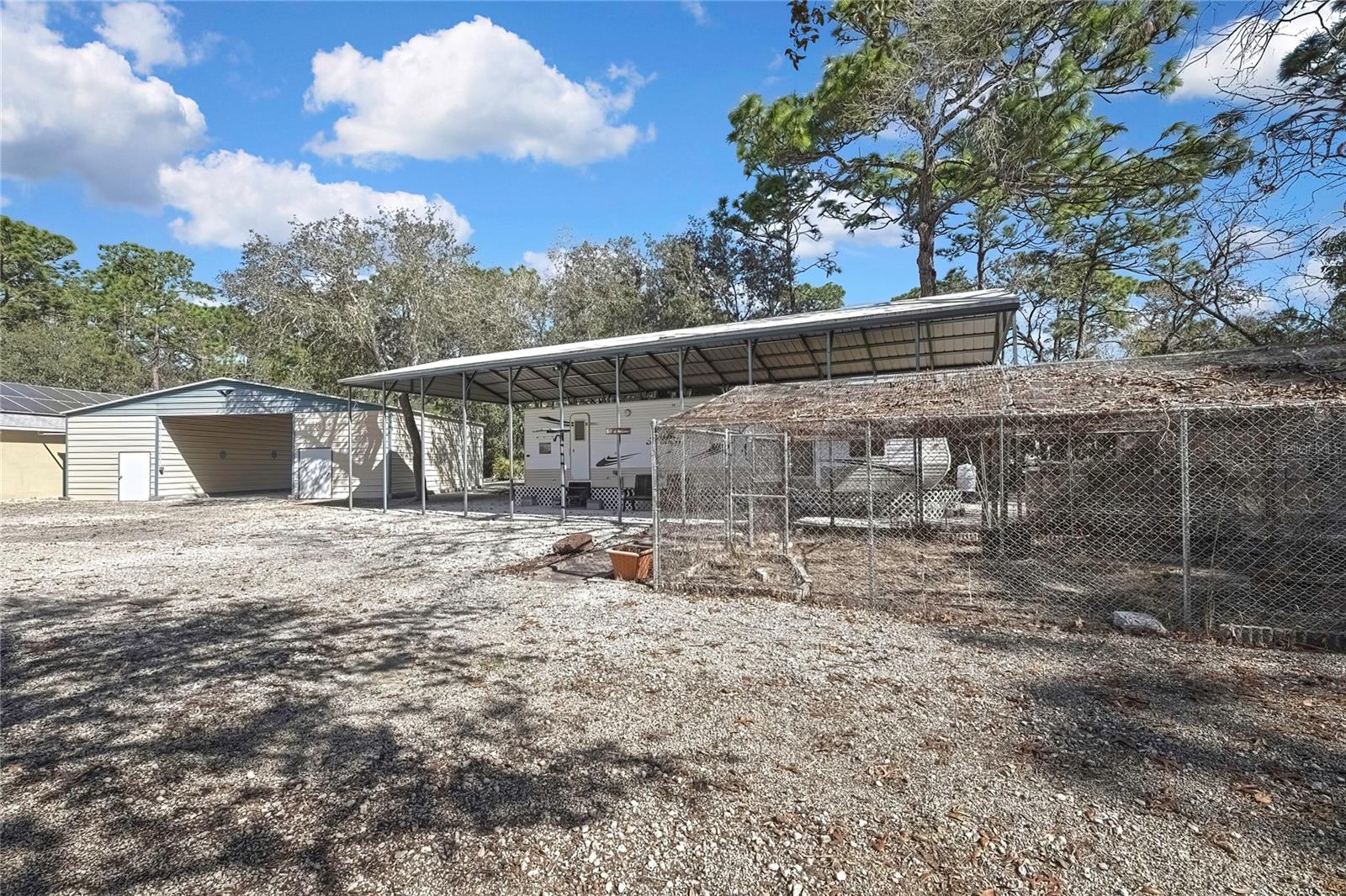 Attatched RV with own Power,  Well and Own Septic with Carport Cover. Enclosed Garden.  Shed #4 & #5 with canopy behind the Seperate 7 Car Garage that Has Solar Panels for House.