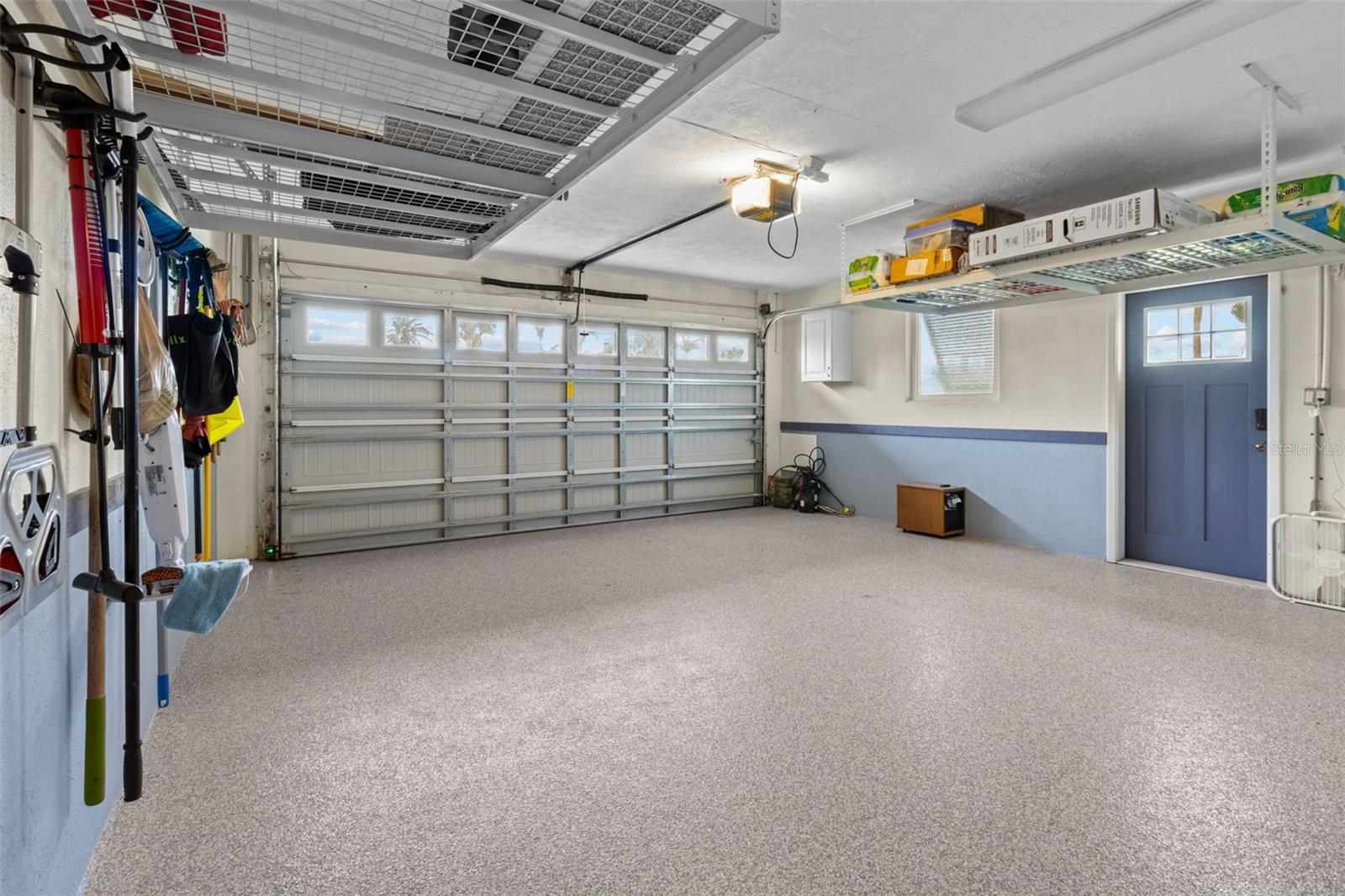 Meticulous epoxy floors and plenty of storage. Hurricane impact garage.  Dog cleaning station is  not shown in this picture but it is at the front of the garage where the washer used to be before renovating to an indoor laundry.