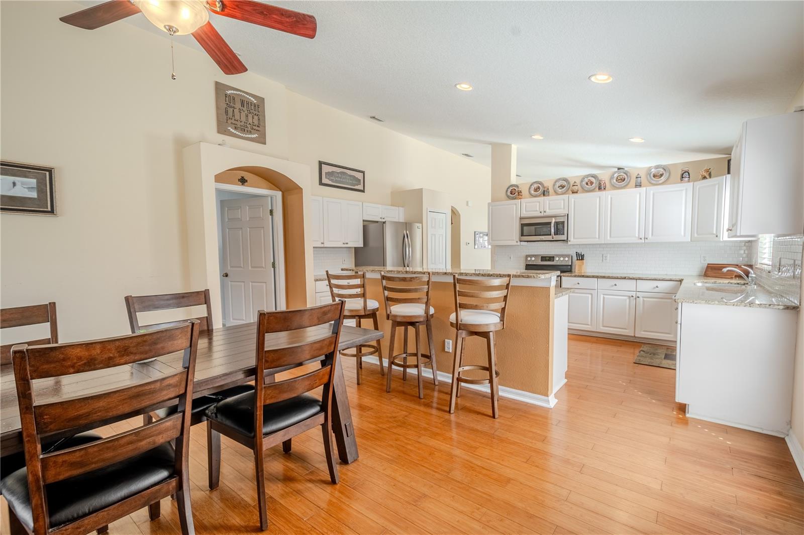 The family room (currently used as a dining area) has wood floors, neutral tones and a ceiling fan with light kit.