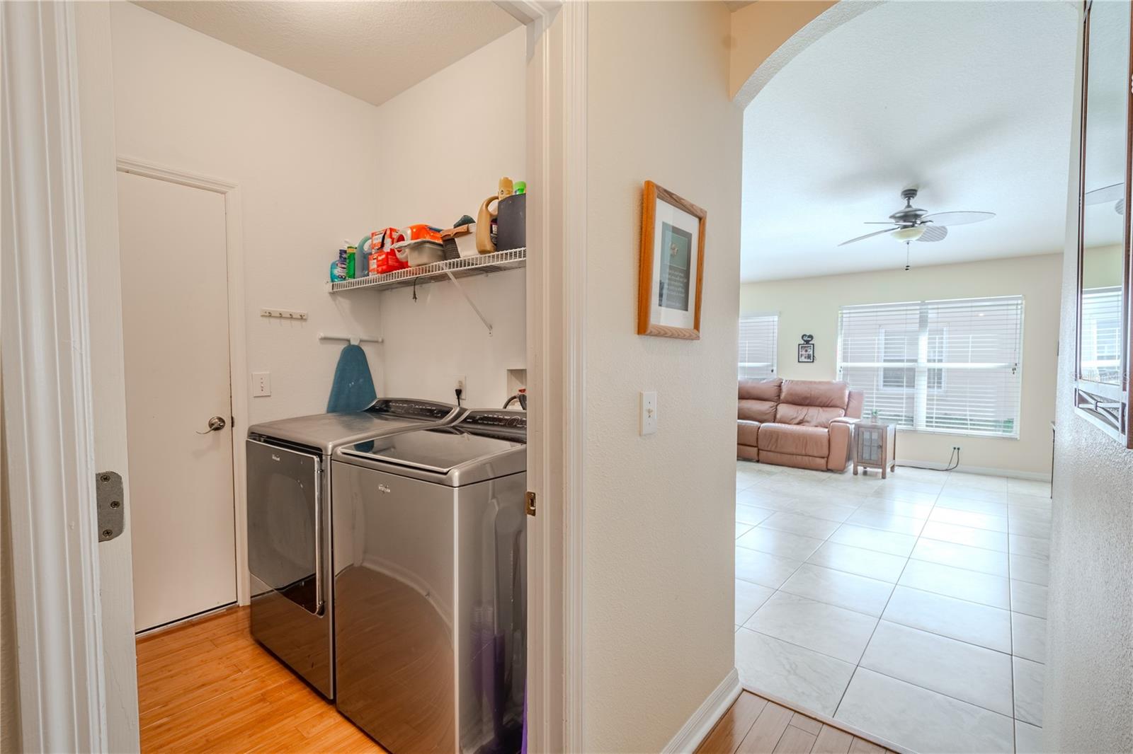 The laundry room features a wood floor, washer and dryer with shelving above.