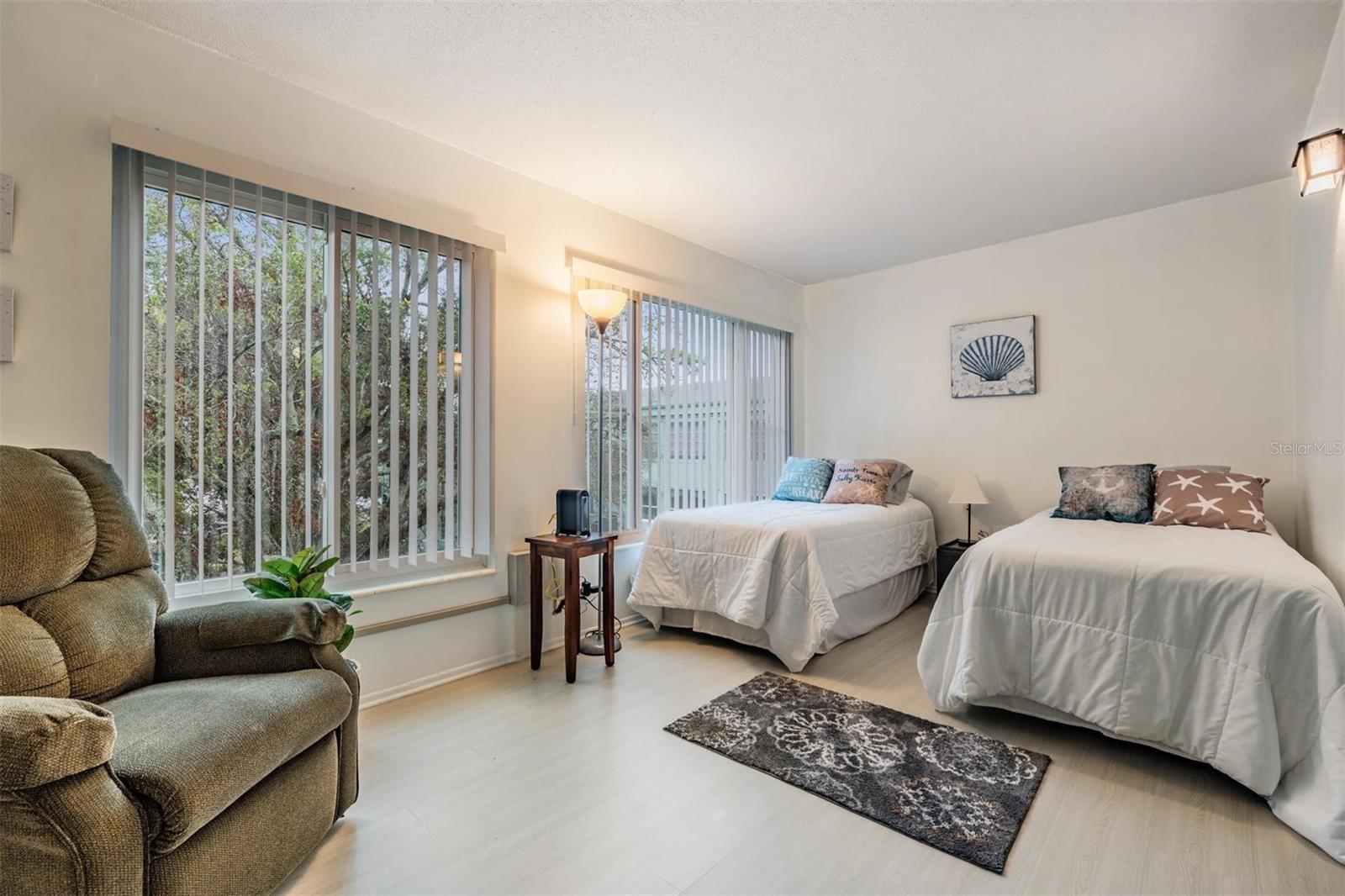 The cozy bonus room at the back of the unit features two large windows and is furnished with two additional beds and provides a relaxing seating area.