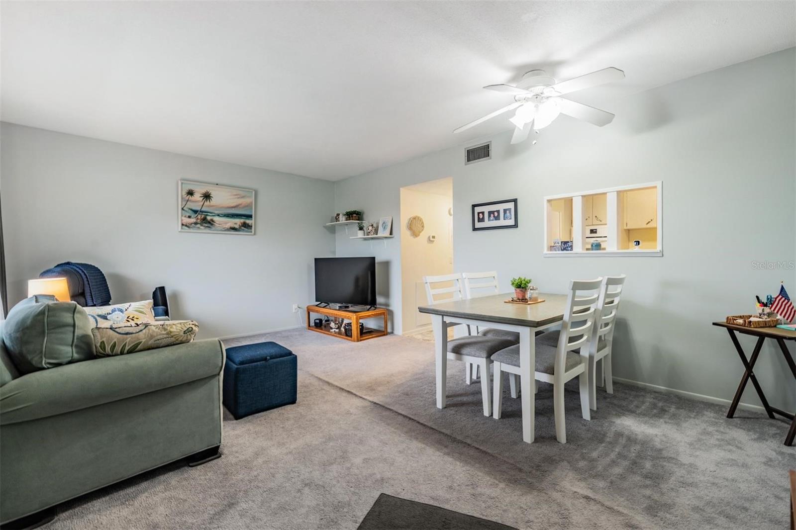 Enter home into Living room / Dining area with large picture windows and a passthrough window to the kitchen.