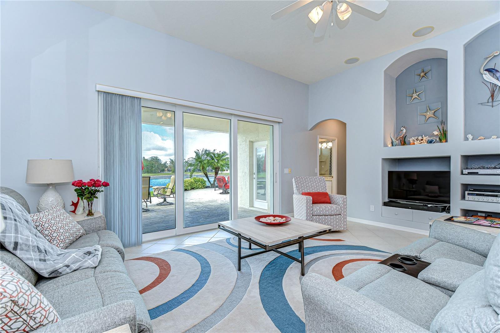 This bright, spacious living room featuring panoramic views of the stunning backyard.