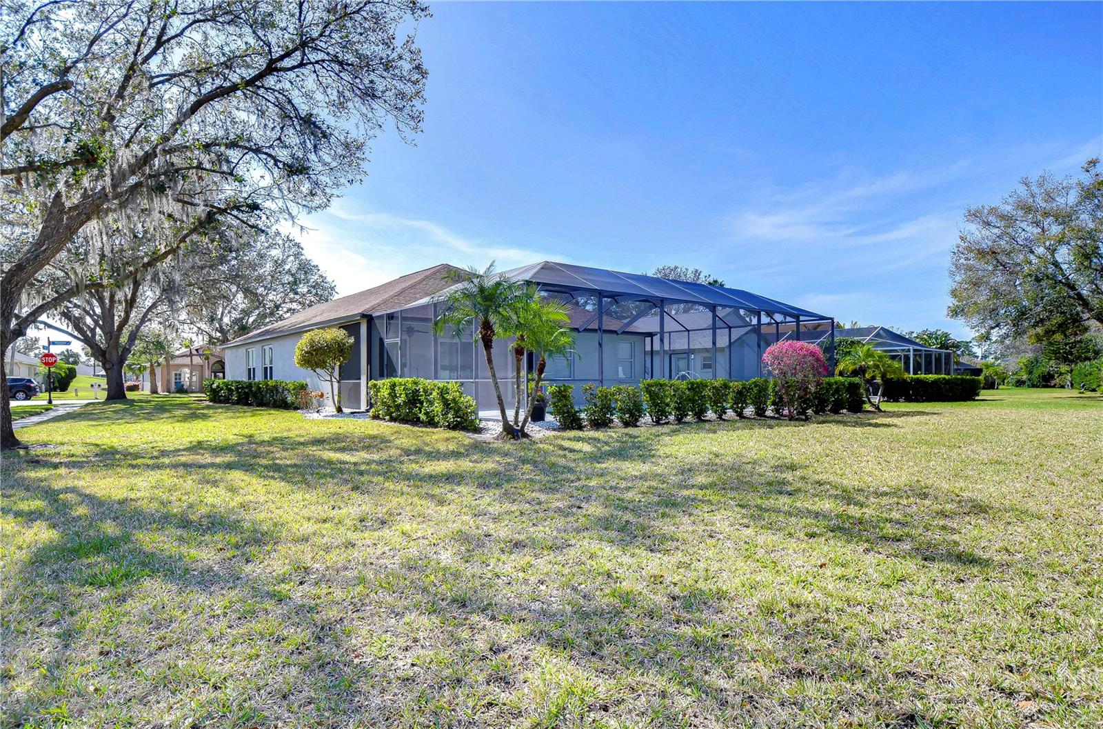 Spacious backyard with lush landscaping and a screened enclosure, offering an ideal spot for relaxation or entertaining guests.