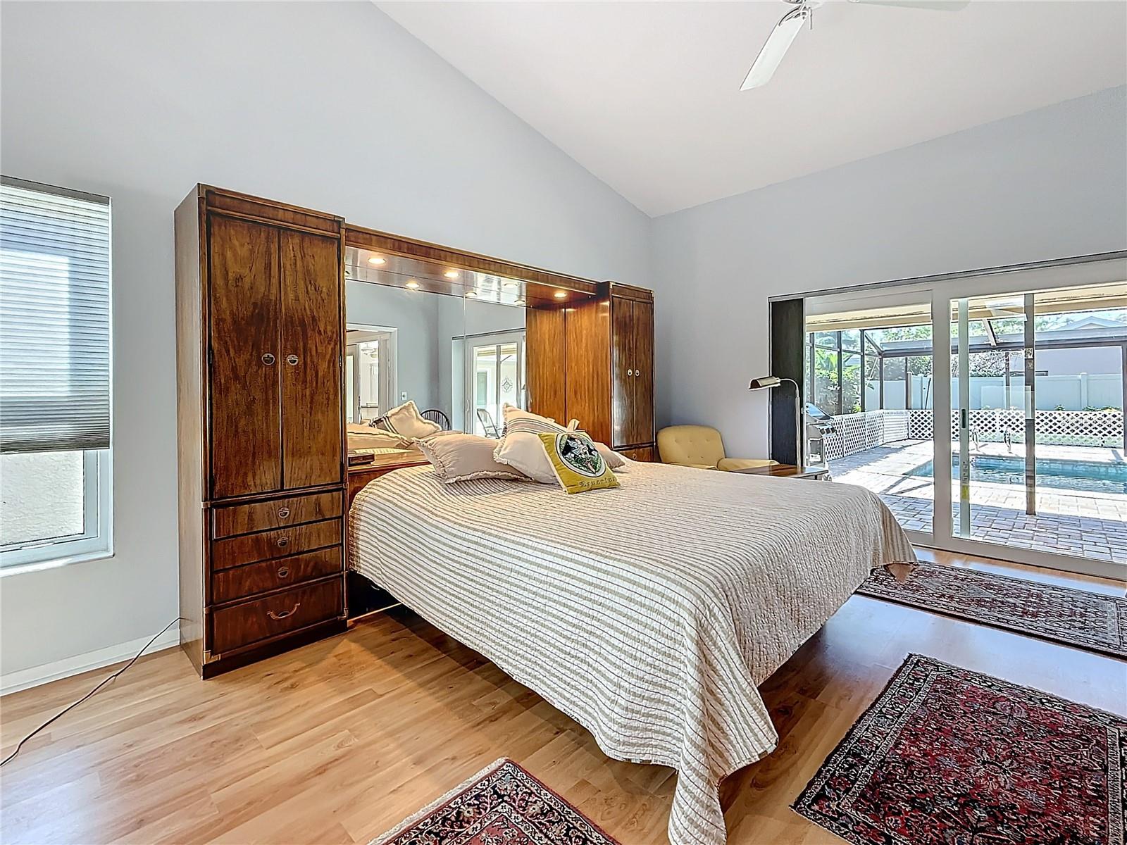 Primary bedroom sliding doors opening to covered, screened  pool area