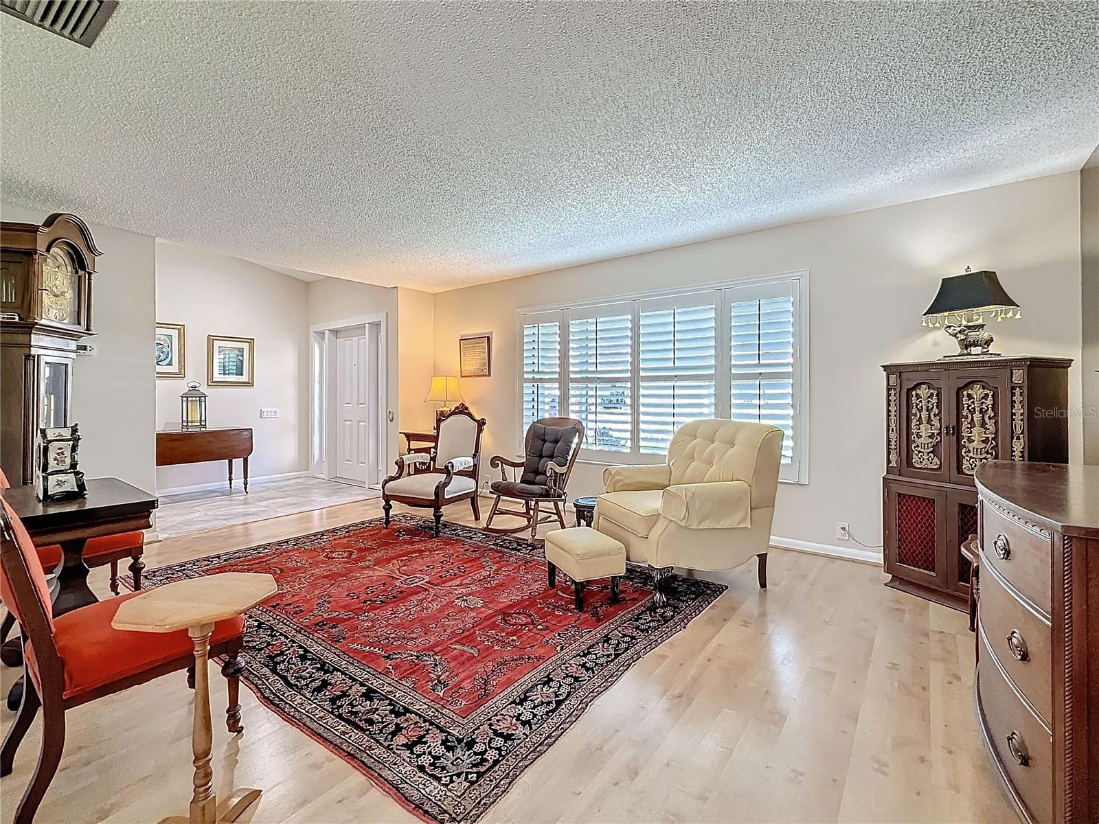 Light filled living room with large picture window and planation shutters