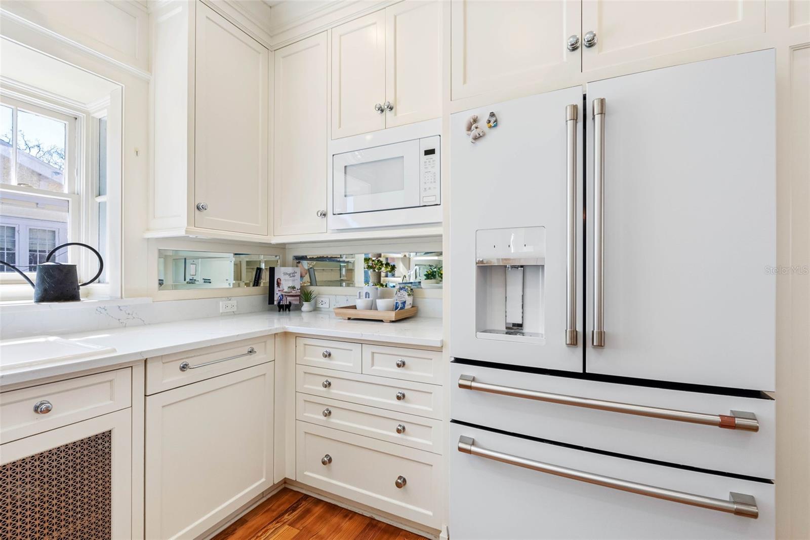 The kitchen features high-end appliances. Café white refrigerator