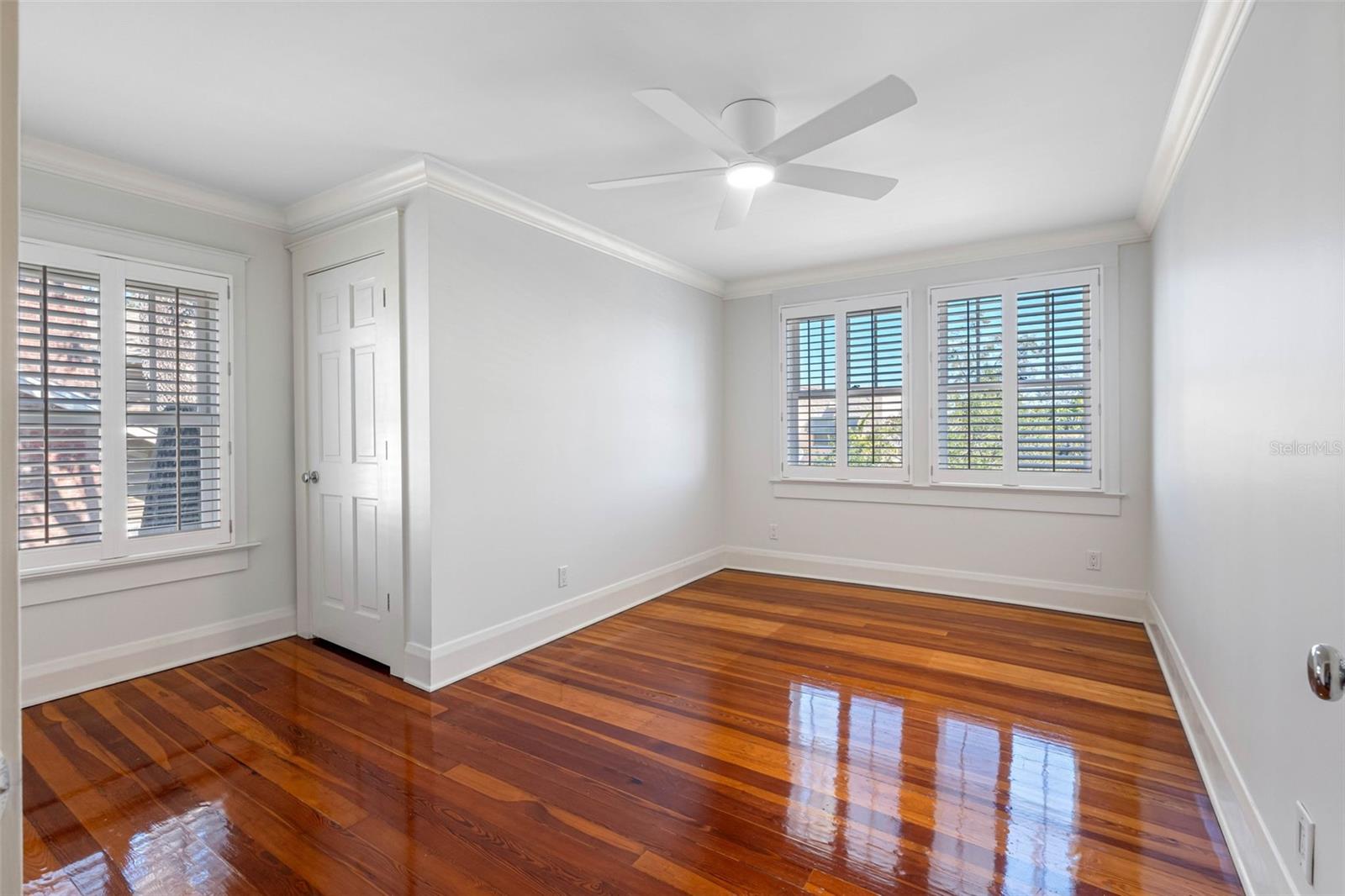 Bedroom #3 (first room you see after landing on the second floor), filled with natural light, plantation shutters, walk in closet, built-ins and ceiling fan.