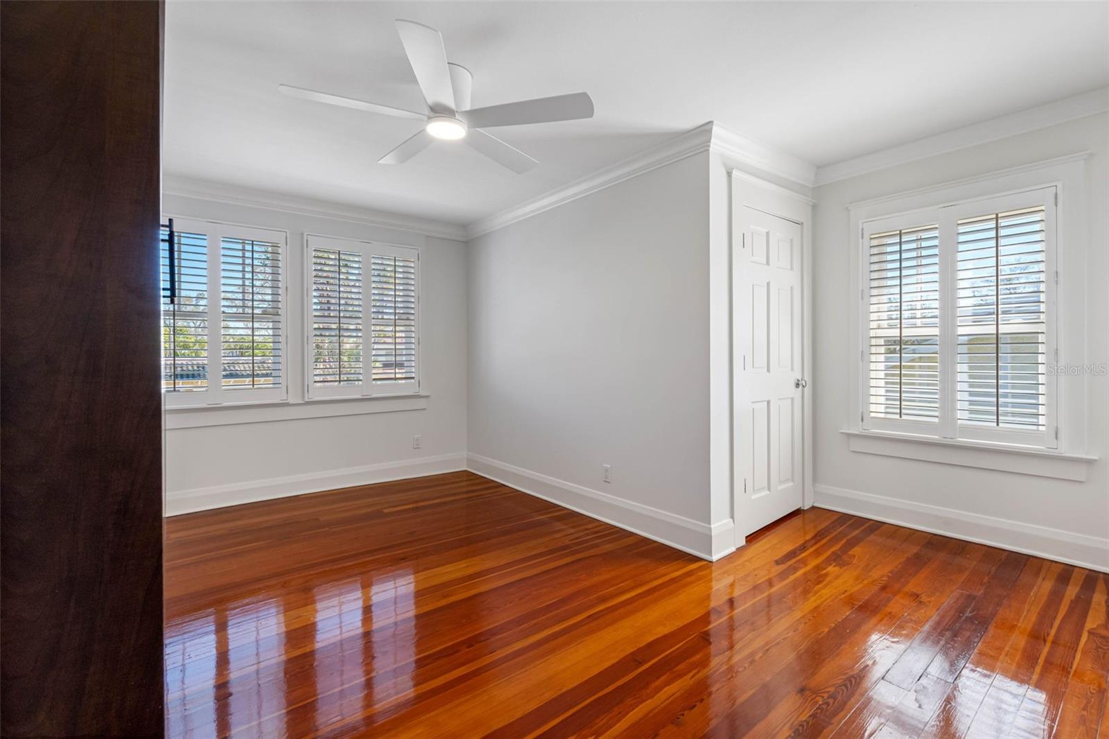 Bedroom #4 (next to #3), filled with natural light, plantation shutters, walk in closet, built-ins, a Murphy bed and ceiling fan.