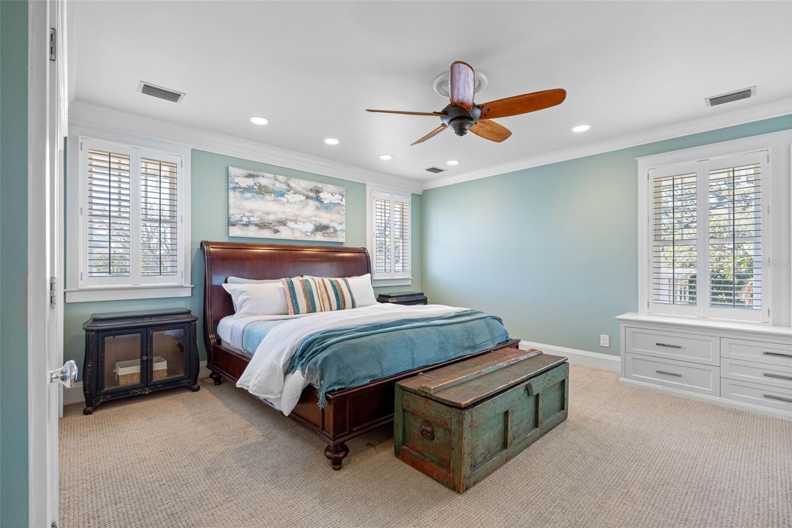 The en suite master bedroom features a  walk in closet, built-ins, additional closets, plantation shutters, and a ceiling fan.