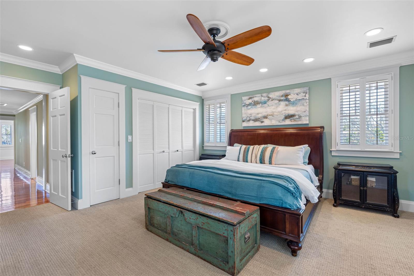 The en suite master bedroom features a  walk in closet, built-ins, additional closets, plantation shutters, and a ceiling fan.