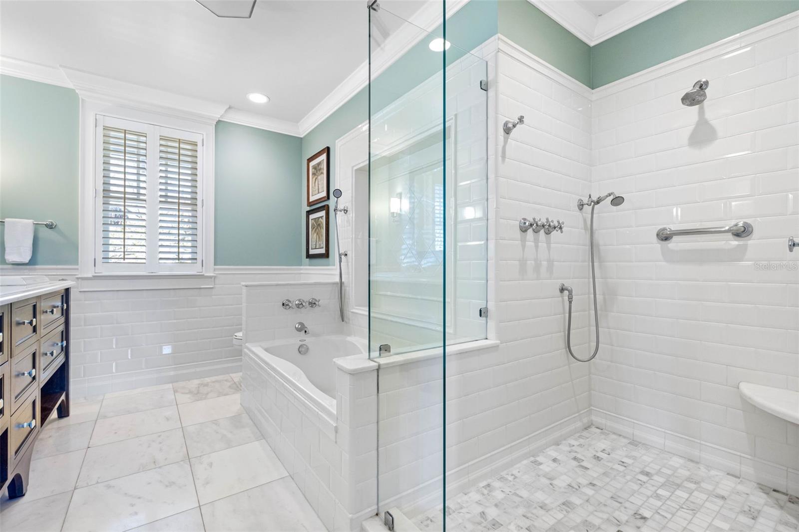 Master bathroom with marble floors and countertop, a dual-sink vanity, a glass shower and a soaking tub.