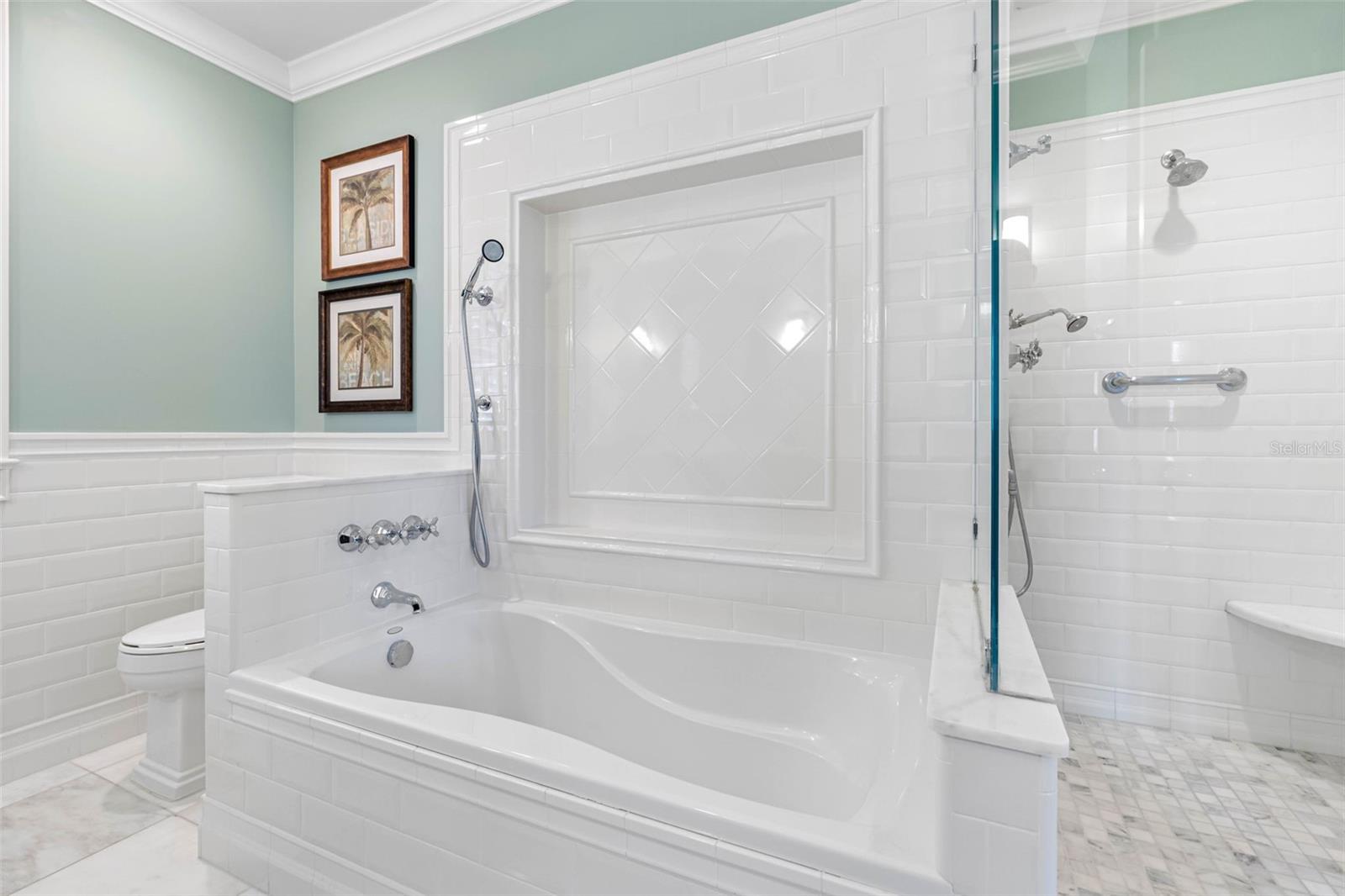 Master bathroom with marble floors and countertop, a dual-sink vanity, a glass shower and a soaking tub.