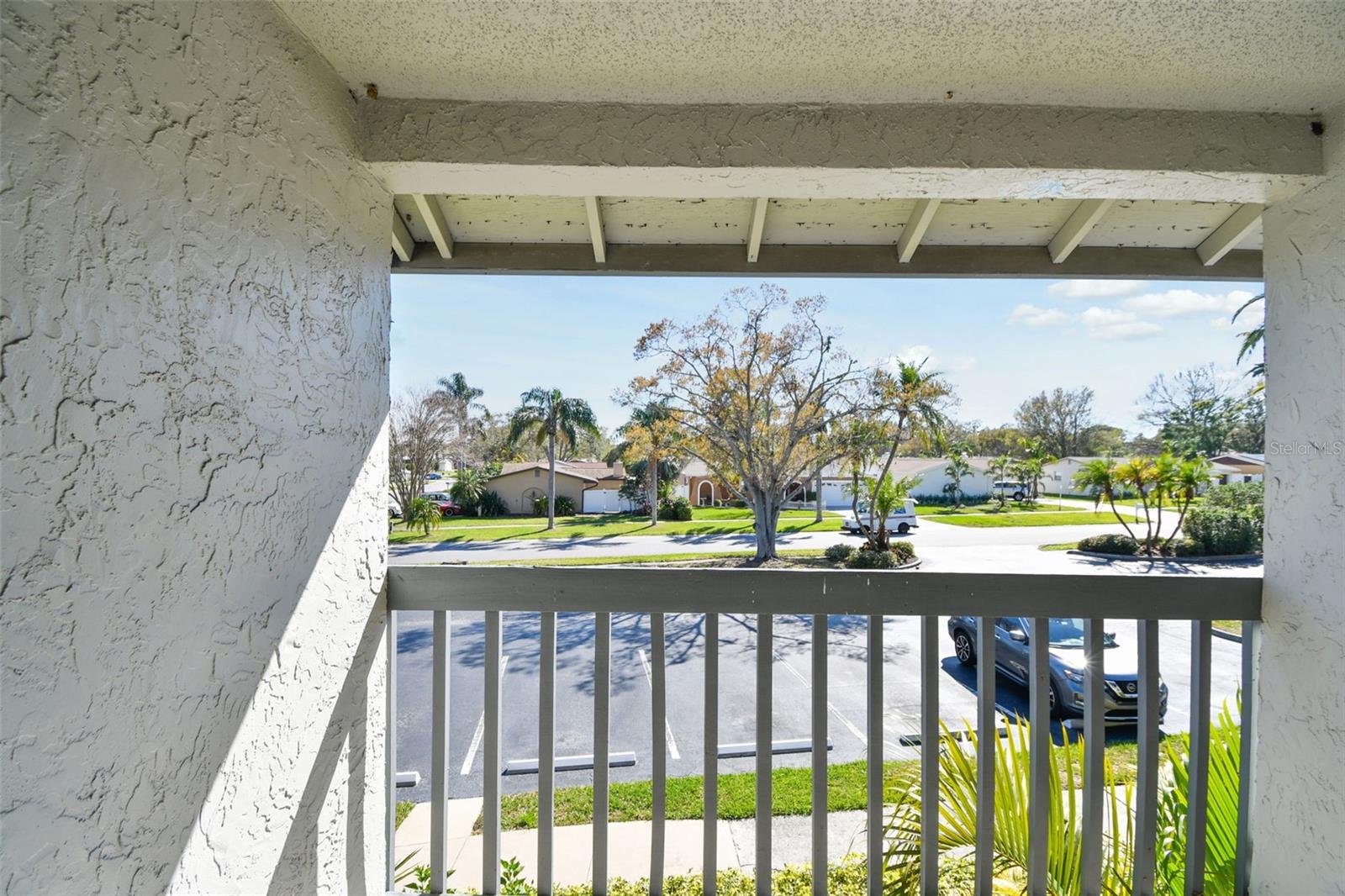 view of parking lot and community entrance from guest bedroom balcony located at the front of the unit.