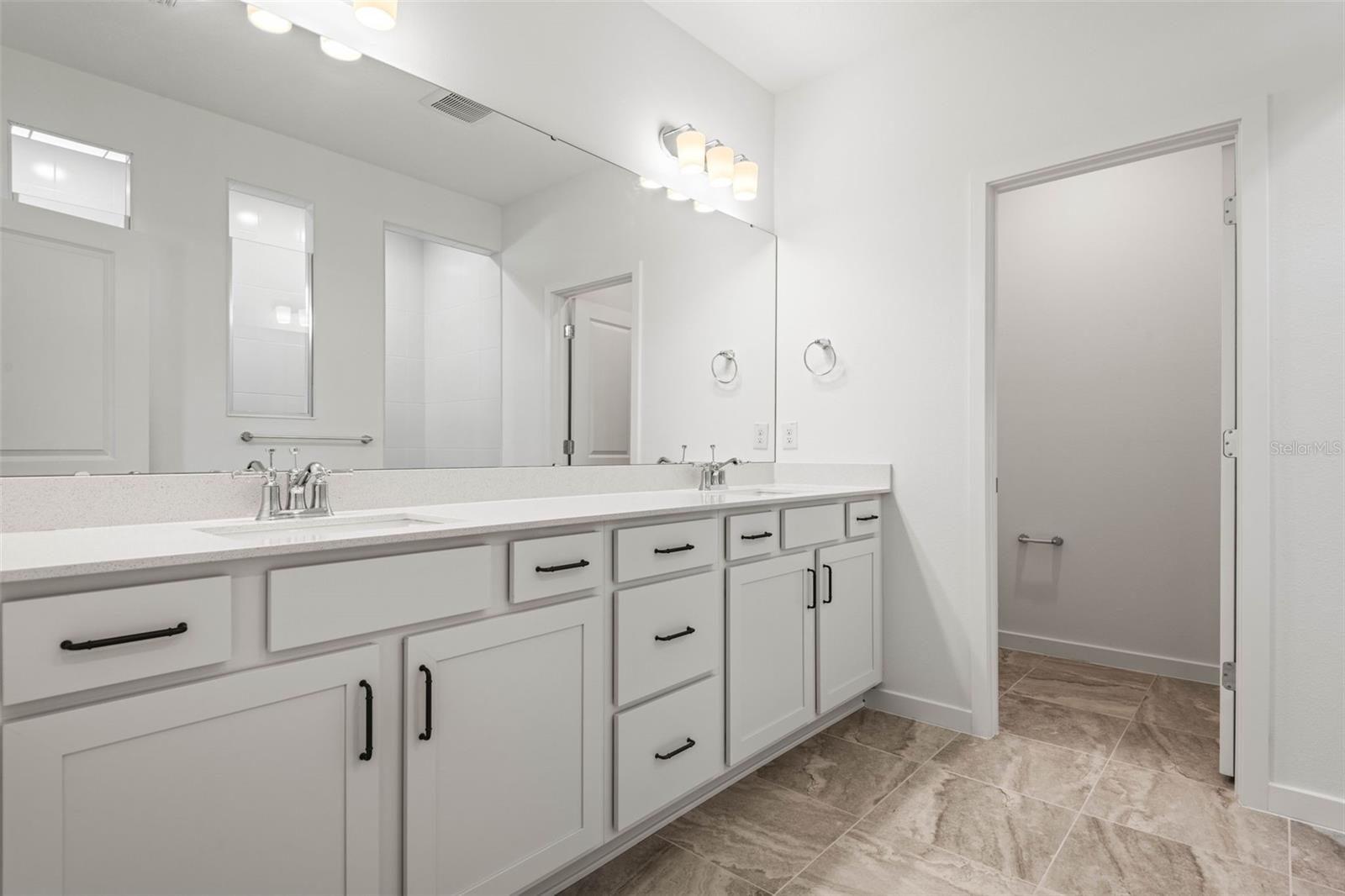 Primary bathroom with dual vanities, quartz countertops and 18" X 18" tile. Comfort height countertops and separate wash closet.