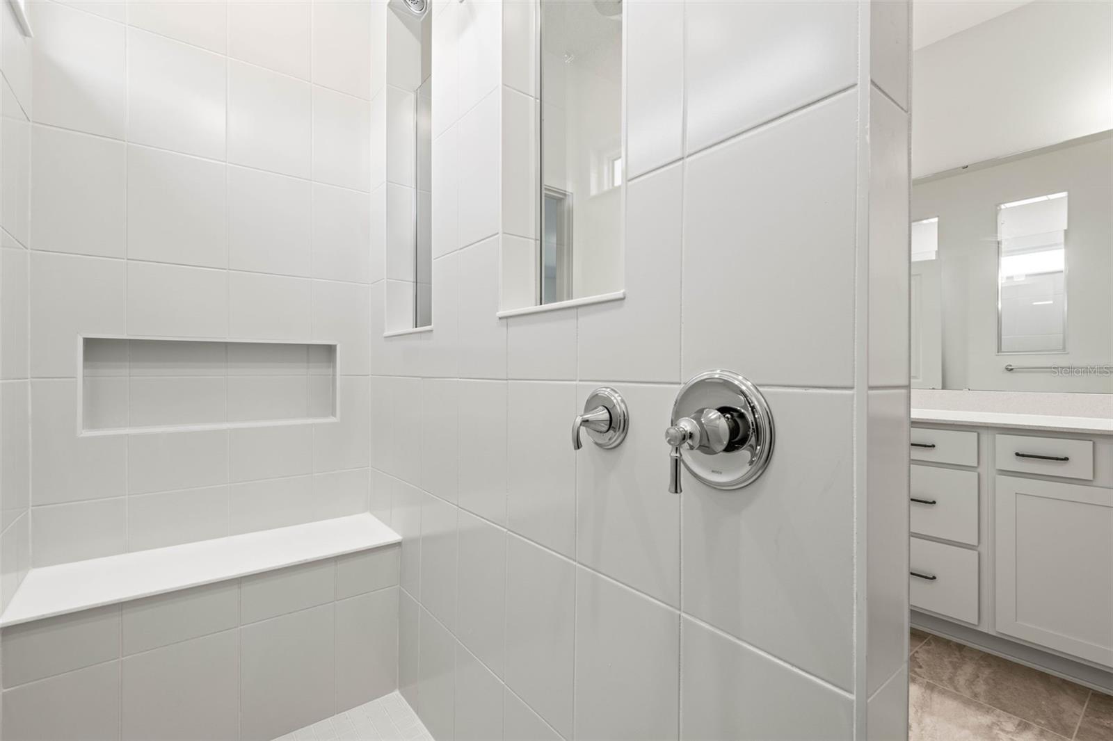 Primary en suite bathroom features a walk in shower with bench and dual shower heads.