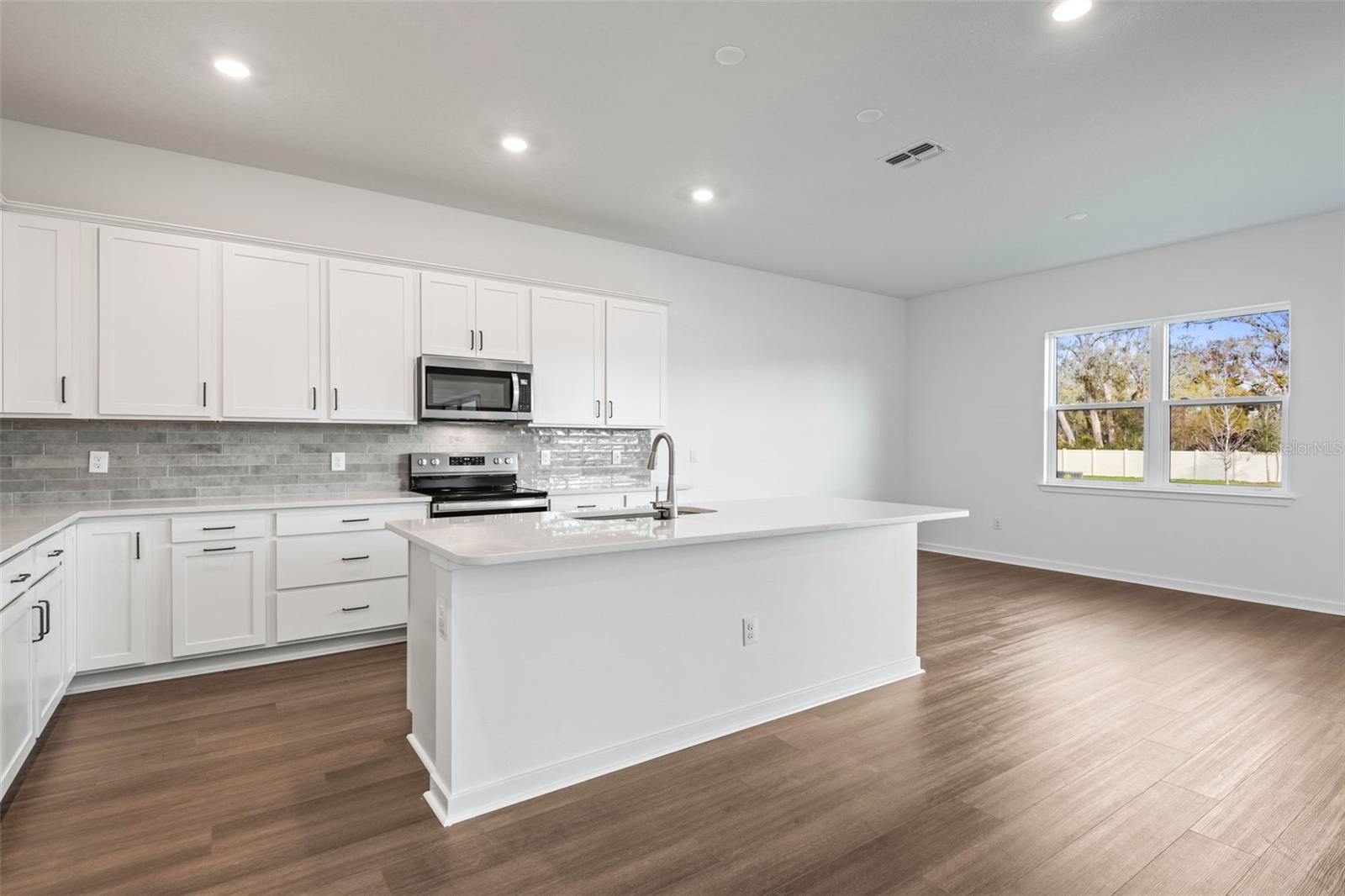 Kitchen with quartz countertops and stainless steel range, microwave and dishwasher.