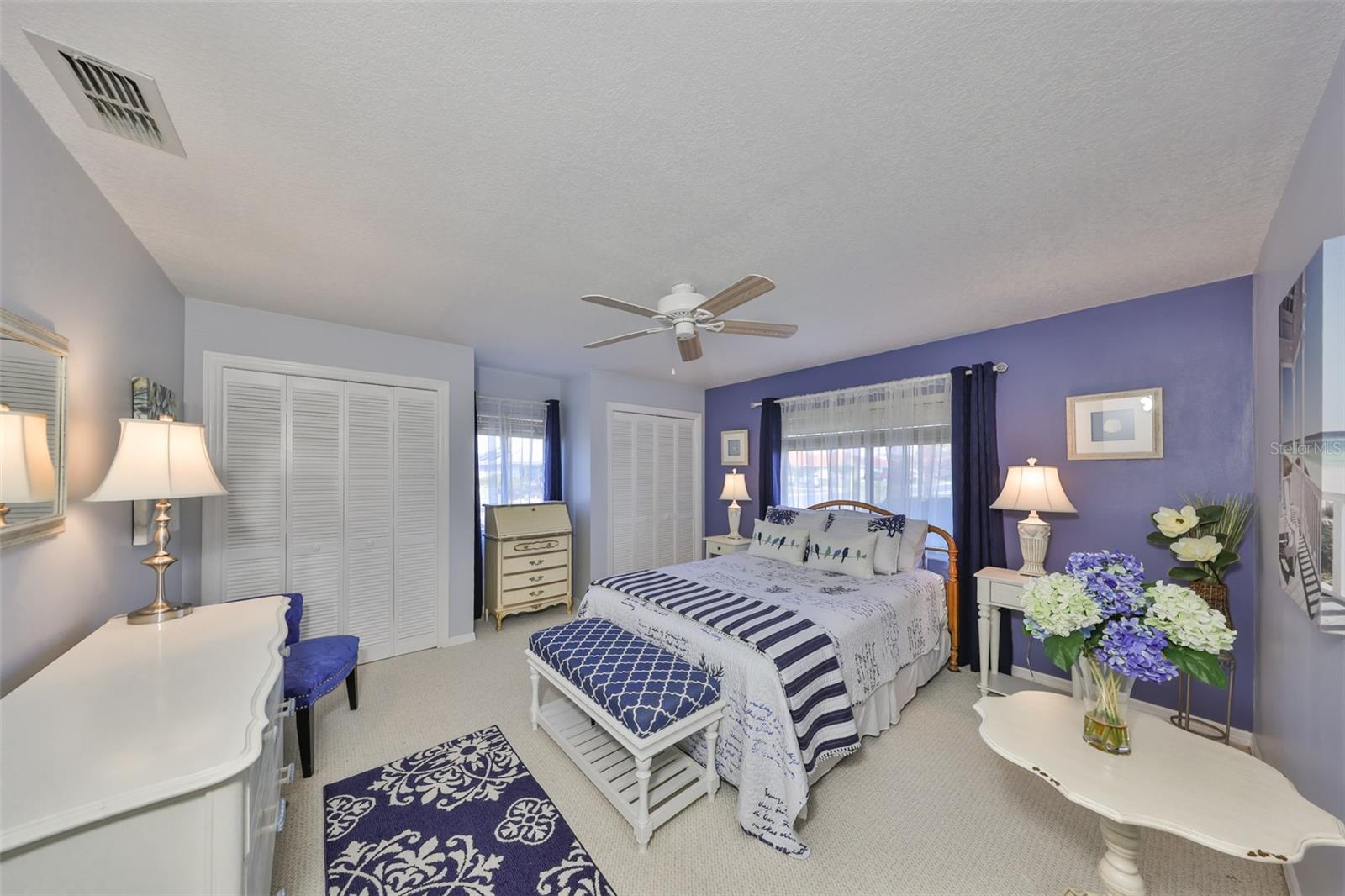 Guest bedroom is large with multiple windows for sunshine.