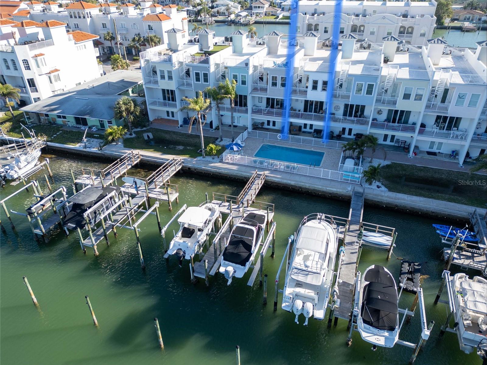 Views from the water with private docks and boats anchored against the backdrop of the sparkling ocean and vibrant sky.