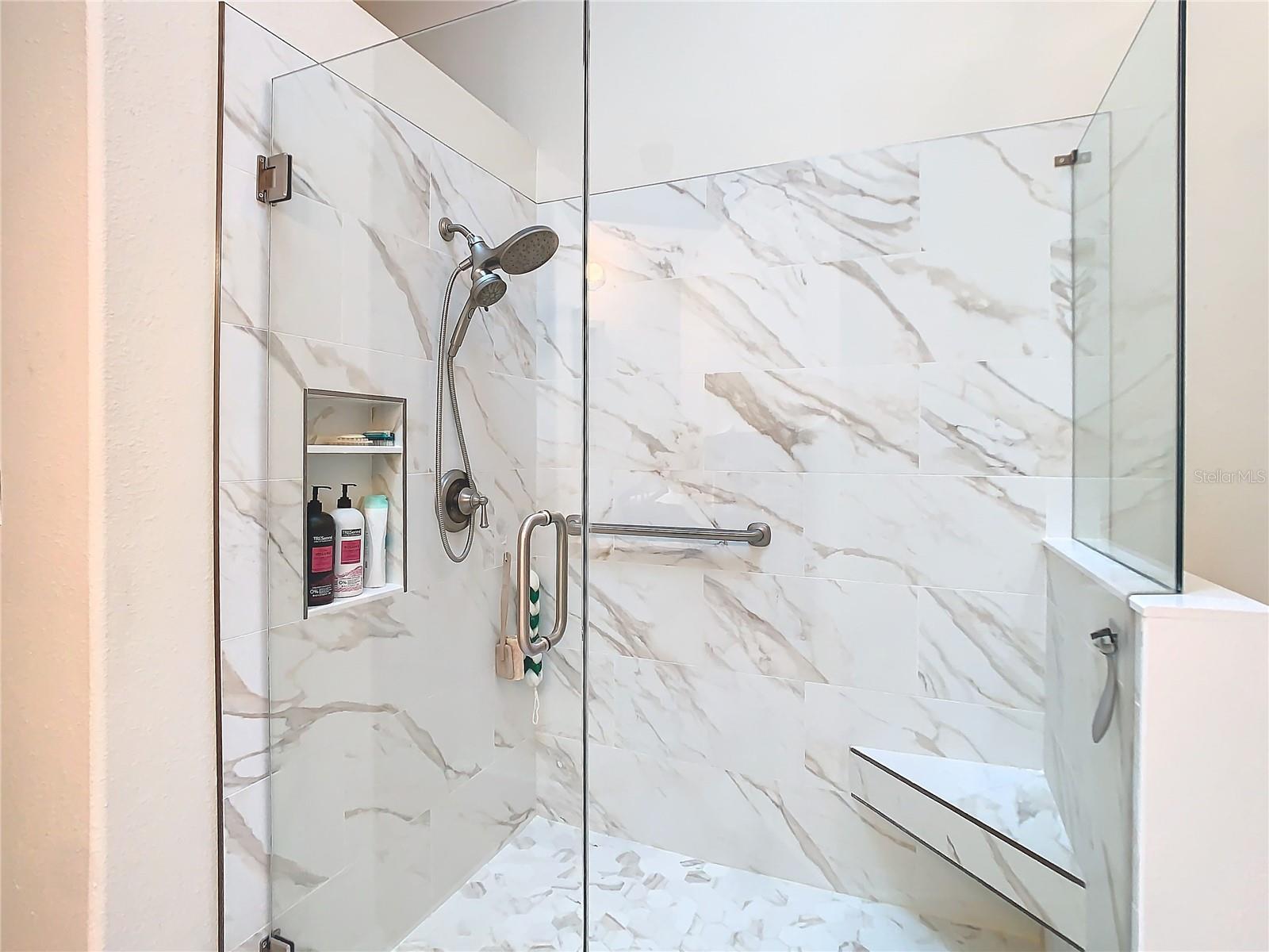 The shower has seamless enclosure, built in shelf and a corner seat to sit on. NOTE: grab bar in place for safety. The room has adequate lighting with a skylight included for that natural light.