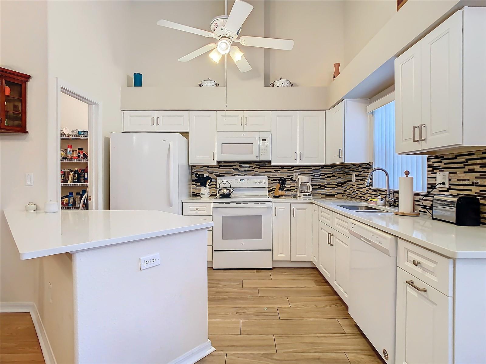 The kitchen remodeled in 2021, has solid surface counters (quartz) and wood cabinets. Plenty of counter space. The backsplash gives the area that "pop" feeling to it. The entire area sits on upgraded ceramic tile.