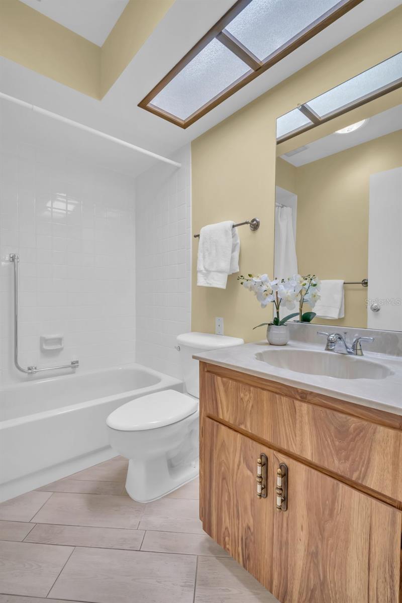 Guest bathroom with updated tub-shower, tile flooring, commode, & fixtures~