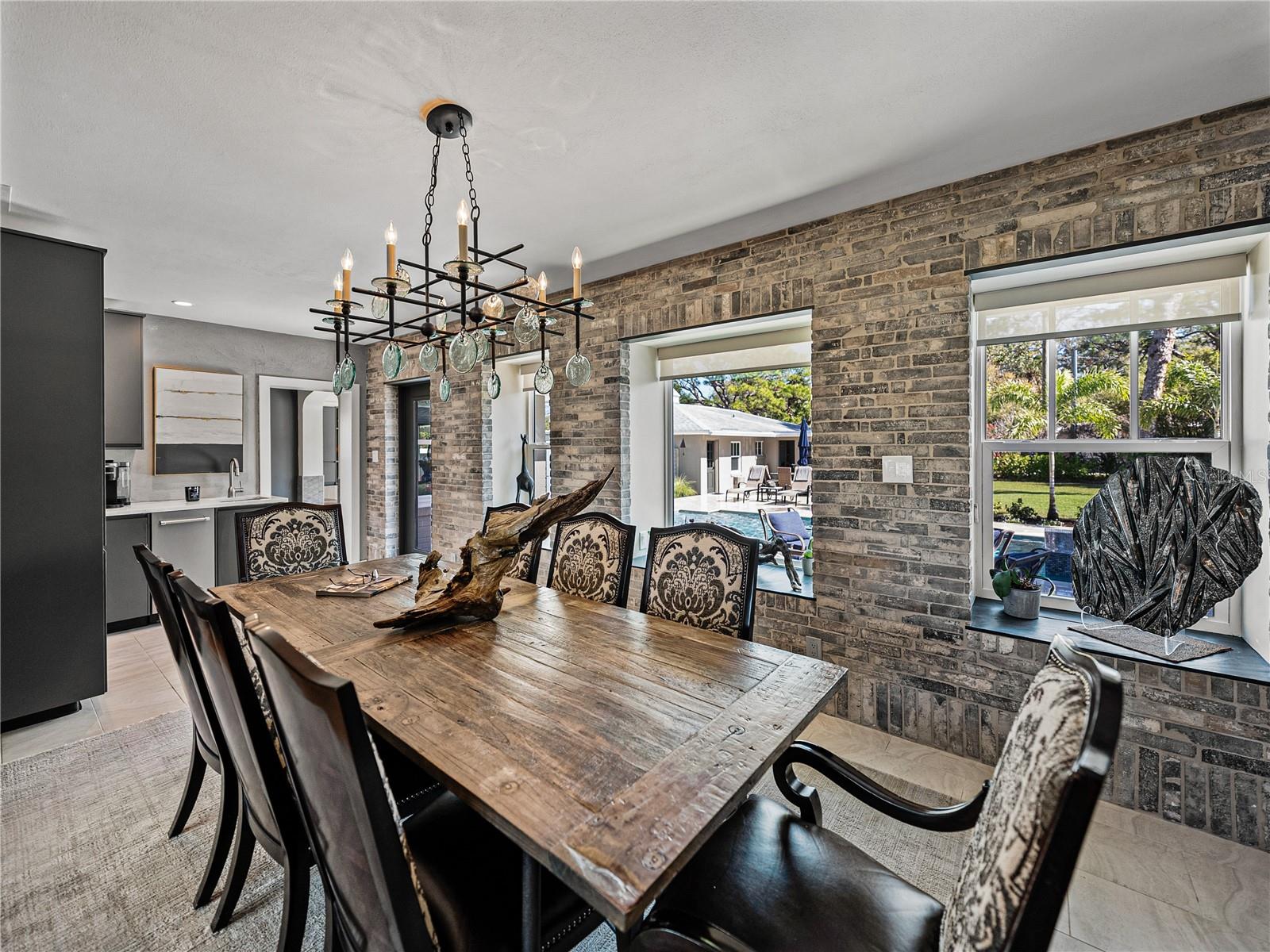 Large dining room overlooking the pool & backyard, with adjacent wet bar featuring Venetian plaster, quartz waterfall countertops, under-counter beverage center and ice maker.