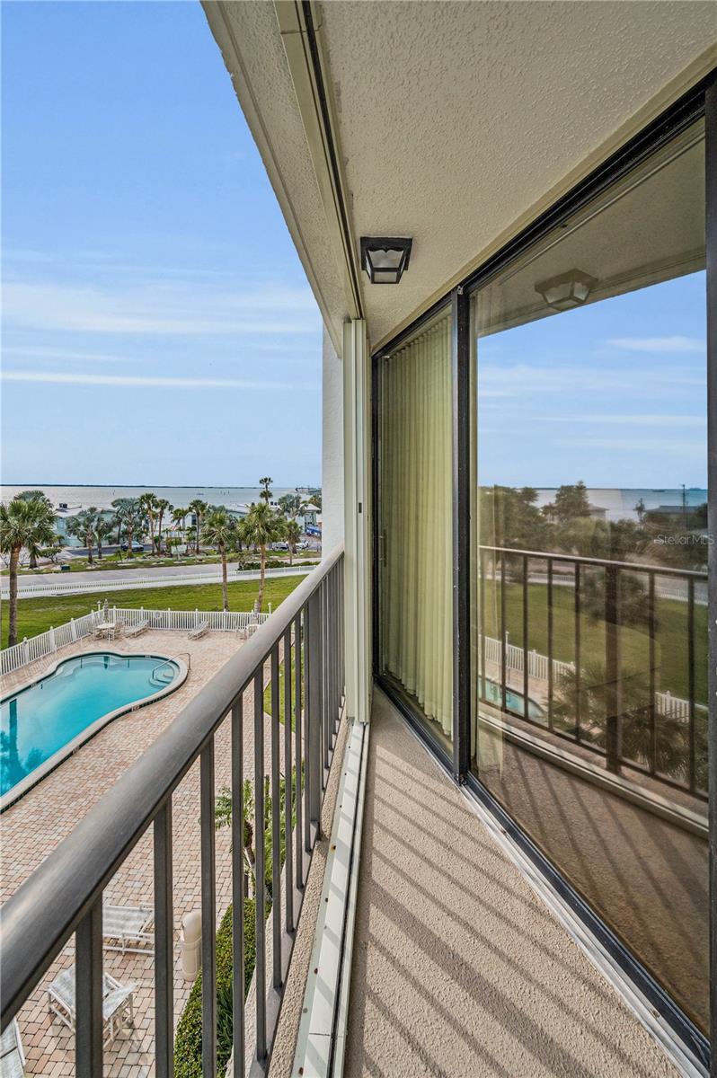 View of master bedroom sliding doors opening to balcony and looking down at pool and out to hurricane pass.