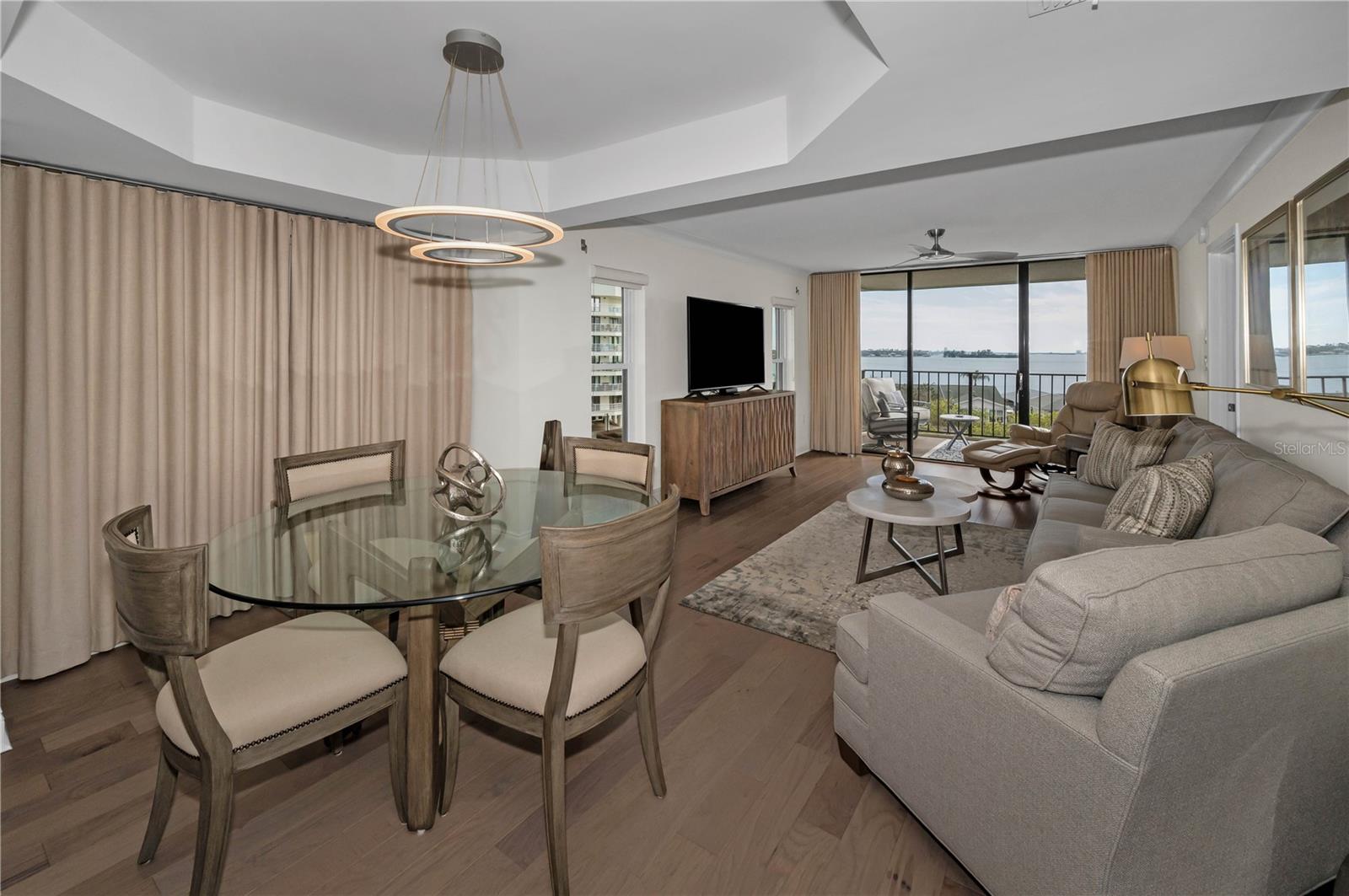 Dining Room area with tray ceiling, modern chandelier, hardwood flooring and lovely modern accents!