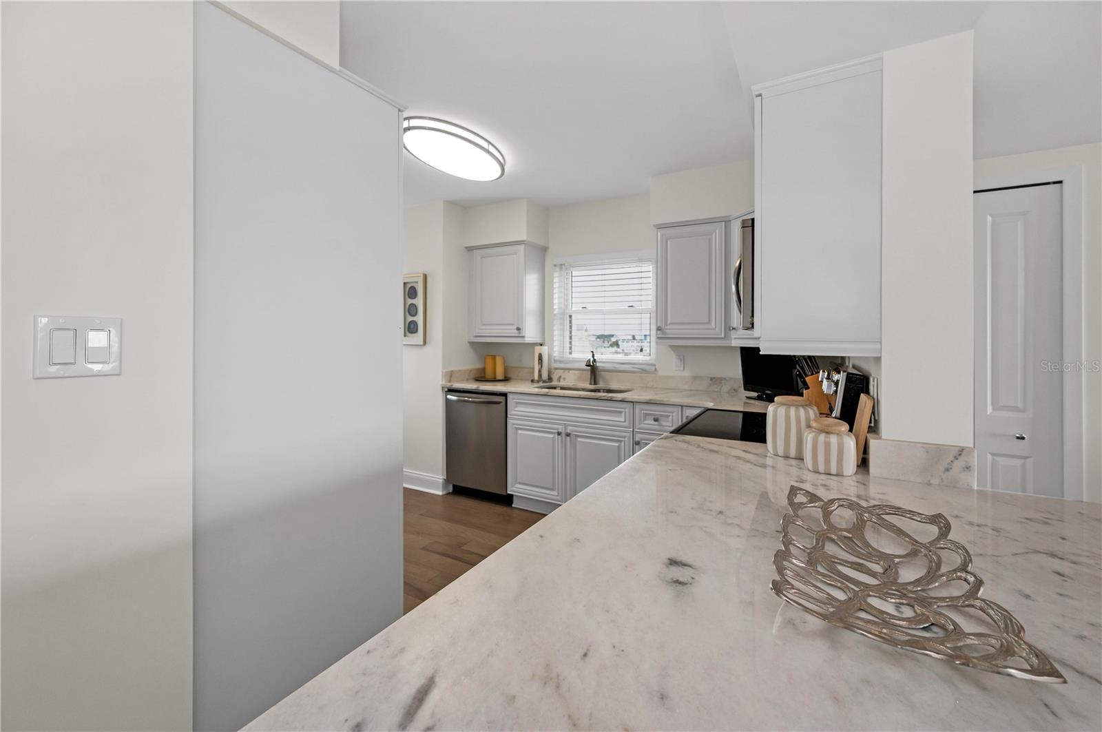 Kitchen with stone counters in white with soft gray, solid wood cabinets.