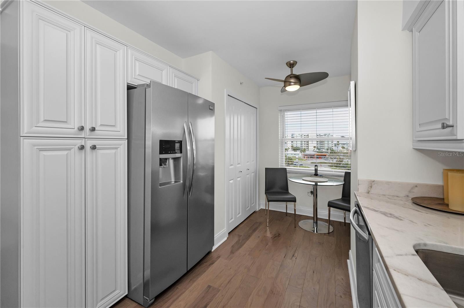 Kitchen cabinet storage areas and closet housing washer and dryer.  Kitchenette at large window.