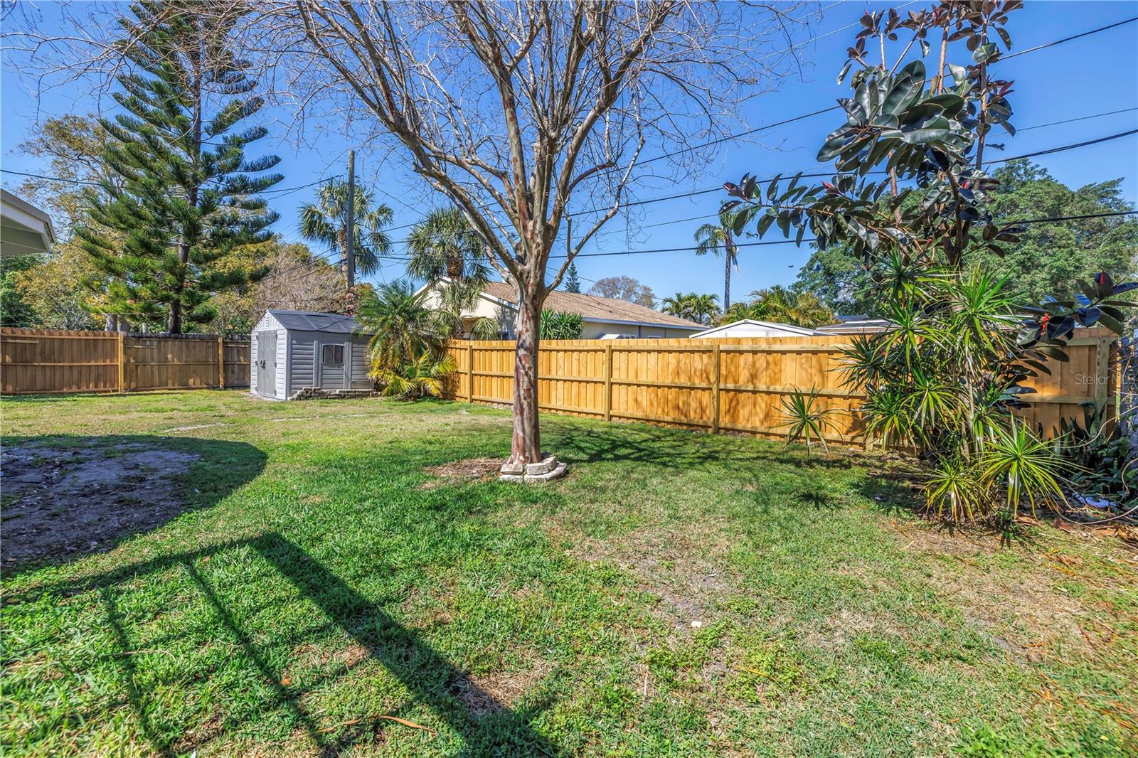 Spacious fenced in back yard with a new fence and storage shed.