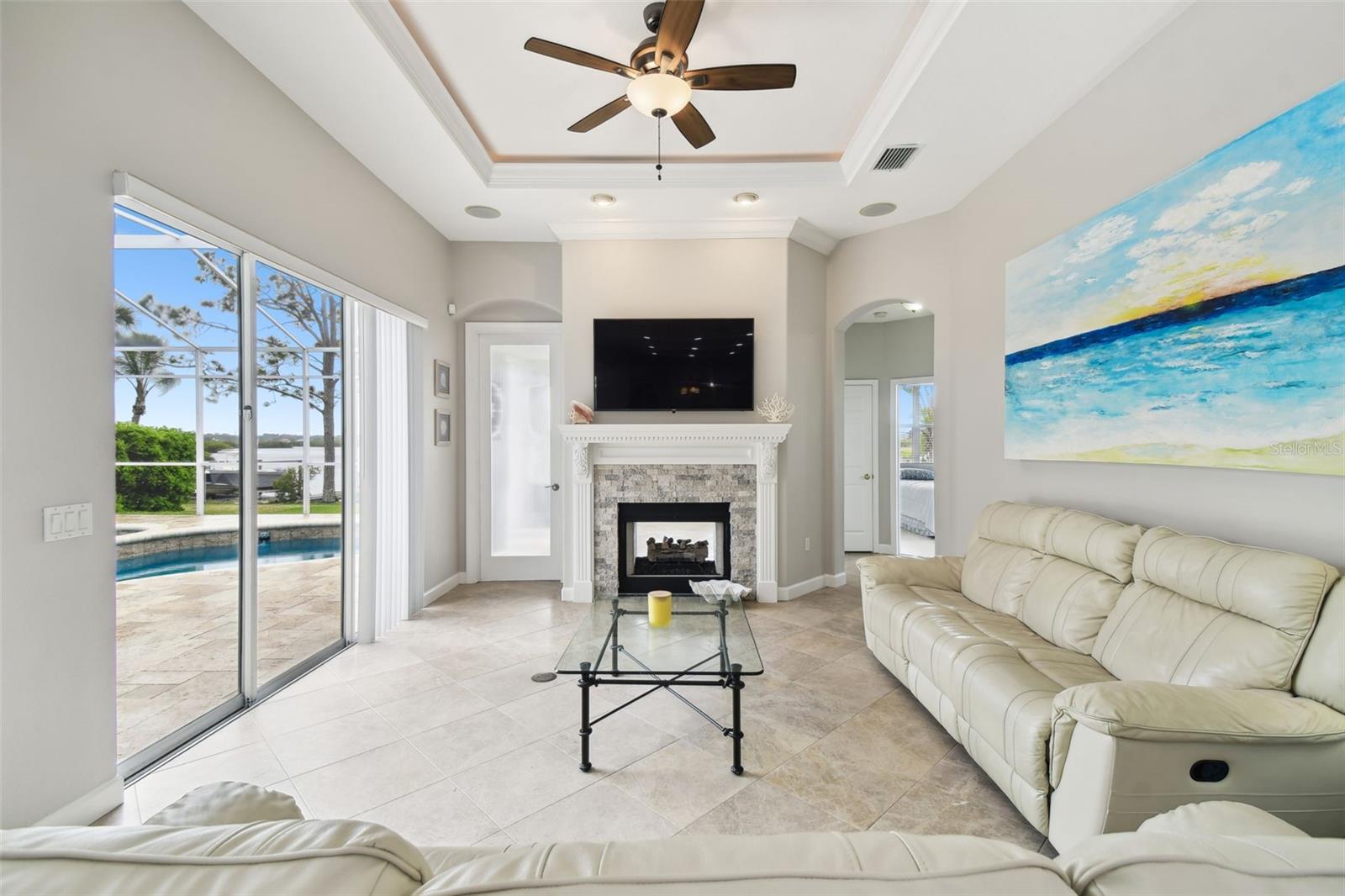 Great room with gas fireplace and pool views. Tray ceilings.