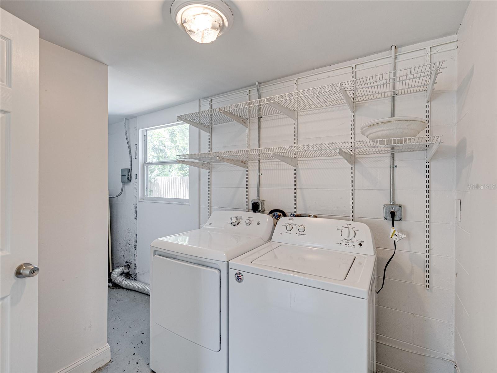 Laundry room has lots of storage space with built in shelfing.