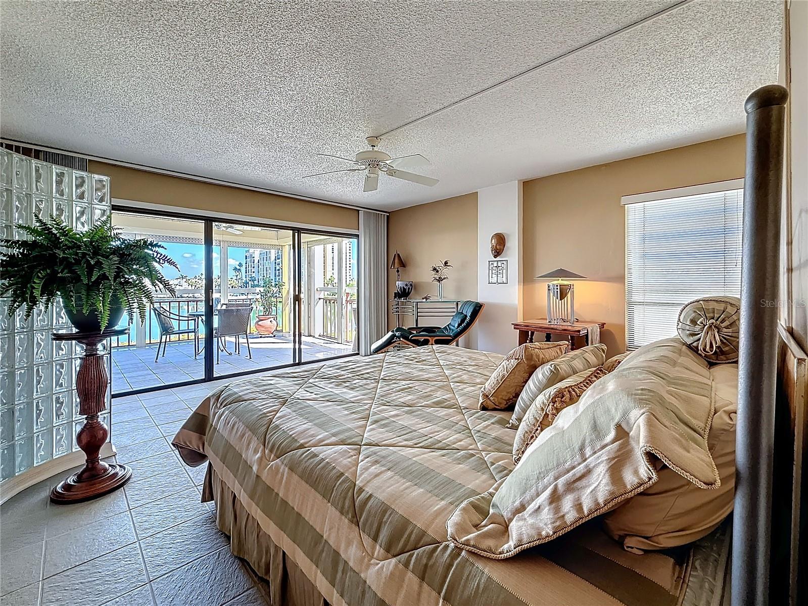 The primary bedroom looks directly out to the water and the patio.  the glass block partition adds architectural interest while maintining an open feel.