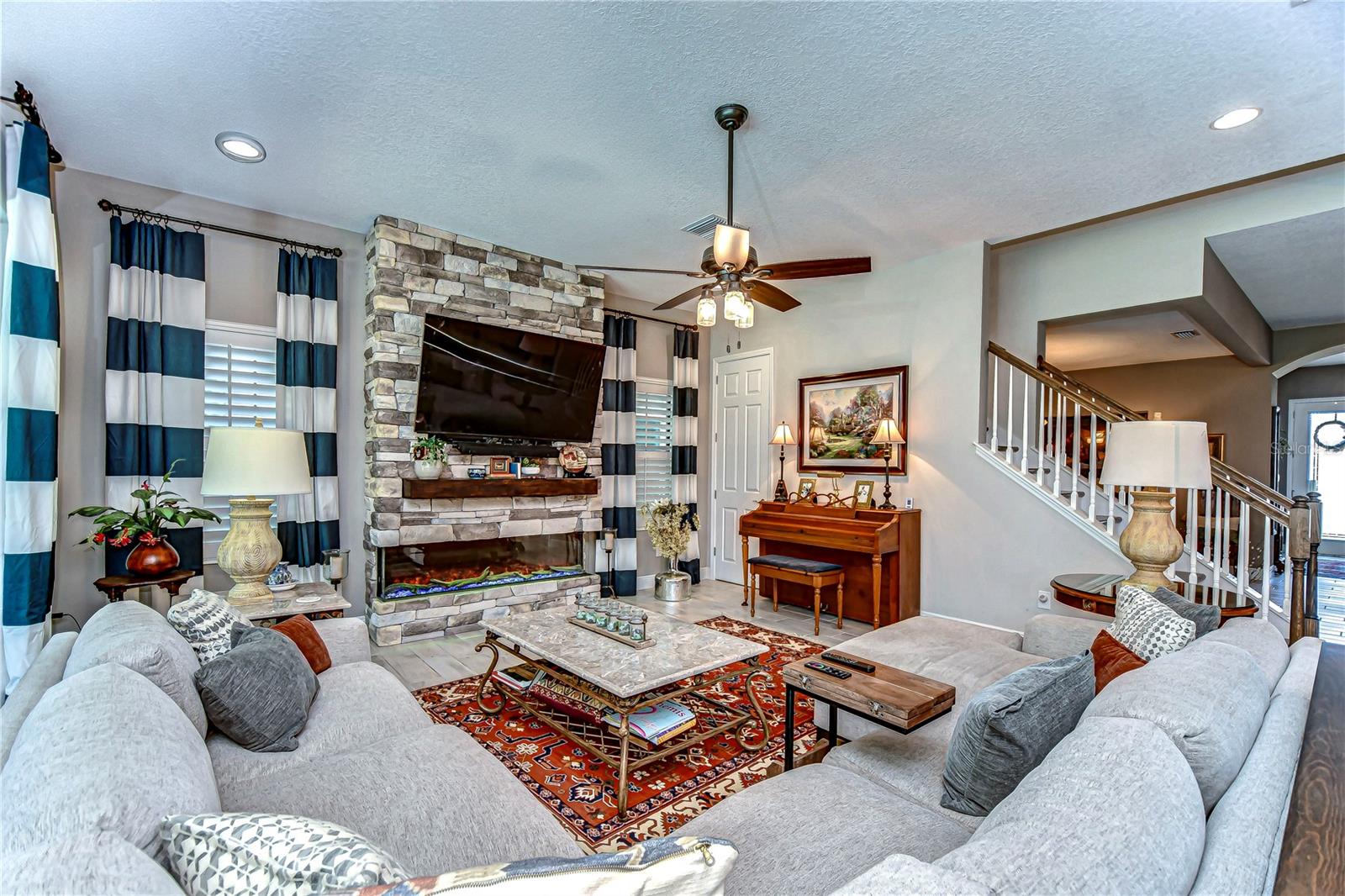 Cozy up in style with this inviting living room, featuring a stunning stone fireplace, and ample space for family gatherings.