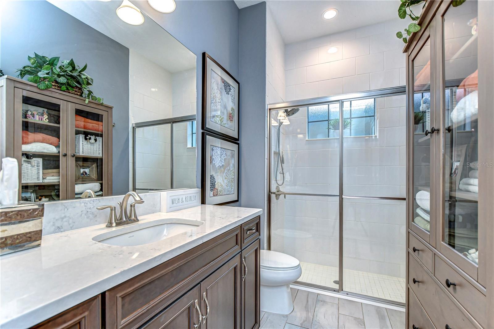 Step into relaxation in this pristine bathroom, featuring a sleek glass shower and elegant vanity.