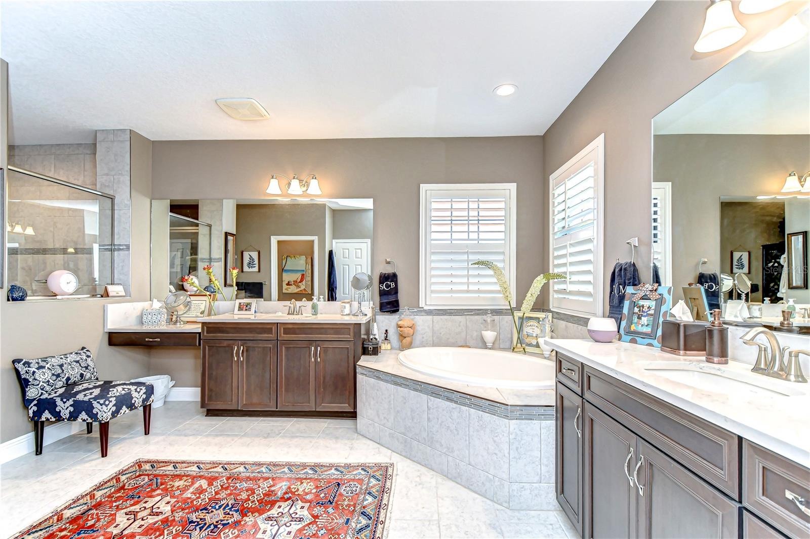 Experience luxury and tranquility in this beautifully designed bathroom featuring elegant lighting, dual vanities, and a deep soaking tub perfect for relaxation.