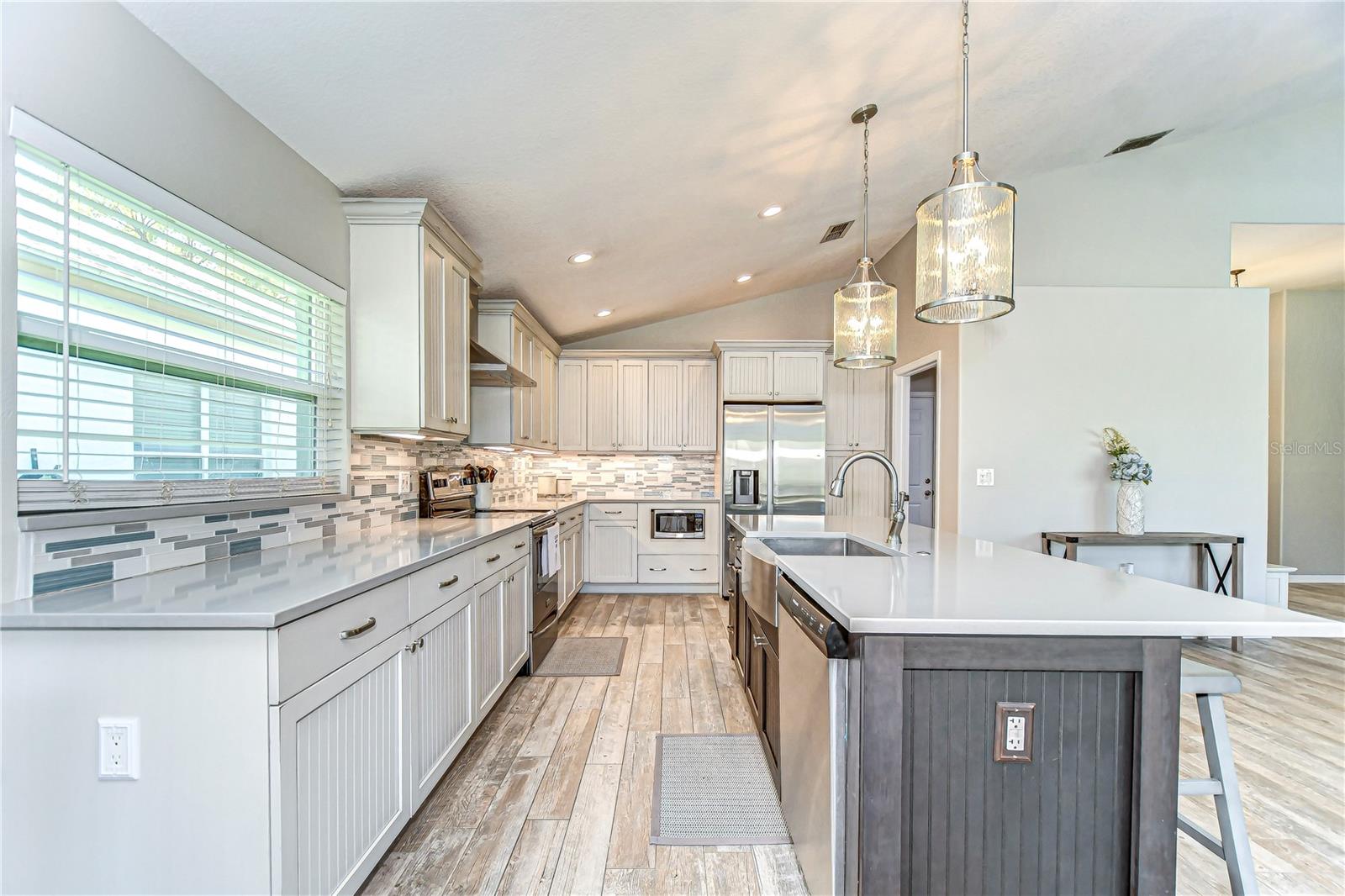 This elegant kitchen blends modern flair with functional design, featuring gleaming countertops and chic pendant lighting.