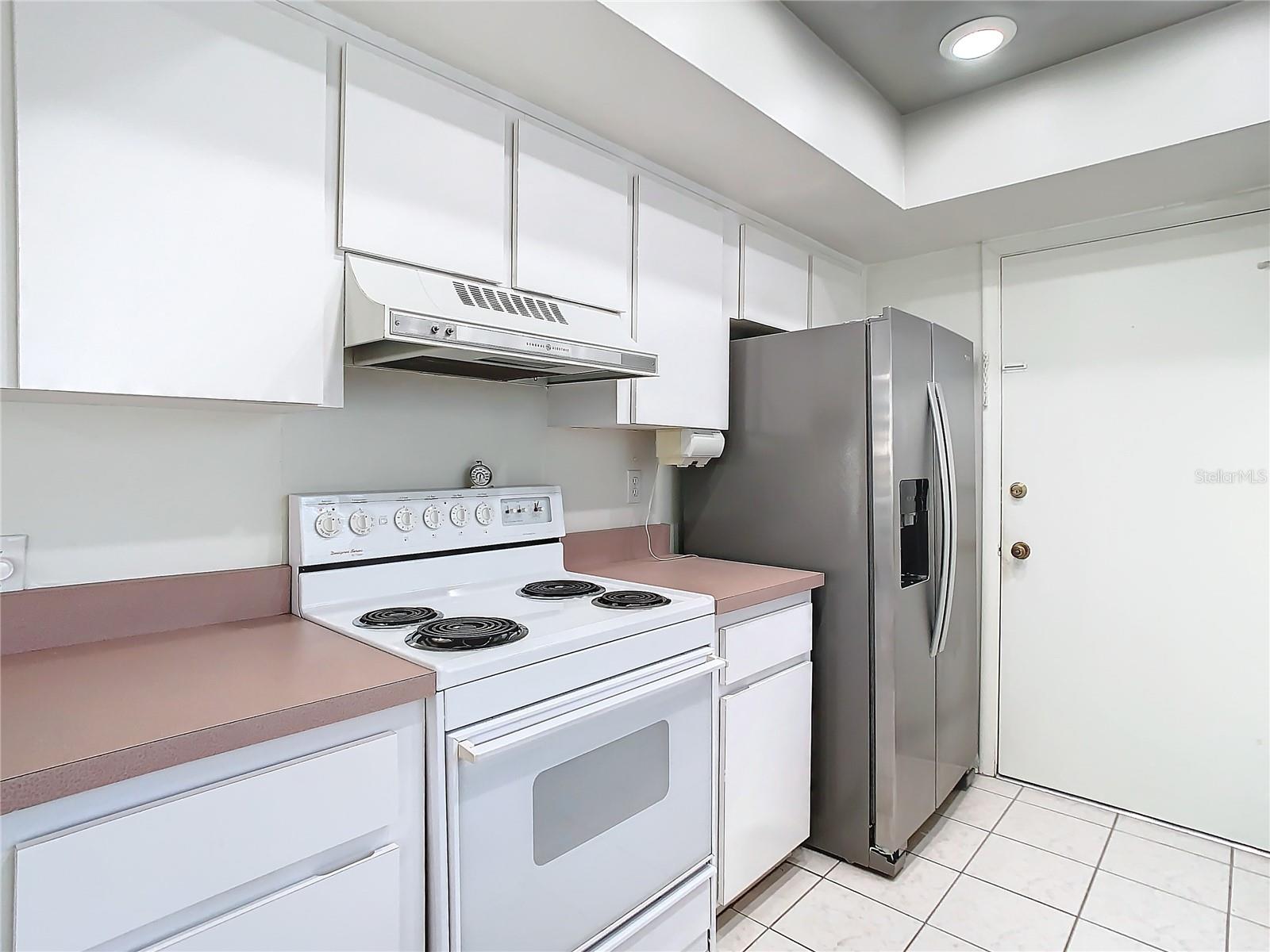 Kitchen showing range and fridge with door leading into garage